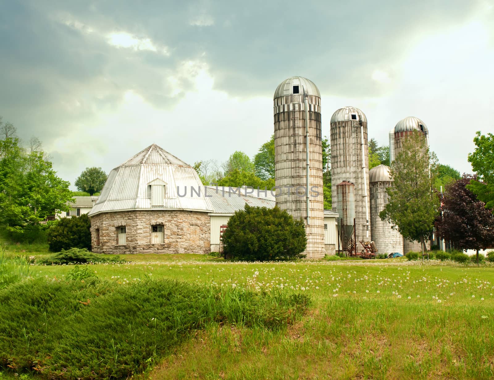 farm with stone barn and silos on a overcast spring day