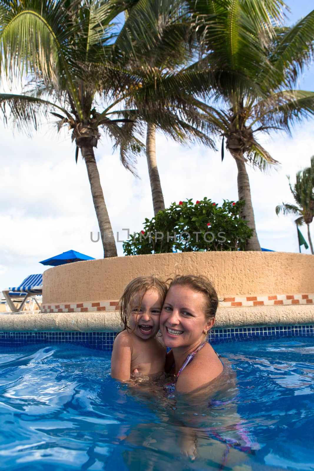 Mother and Daughter laughing in the pool by coskun