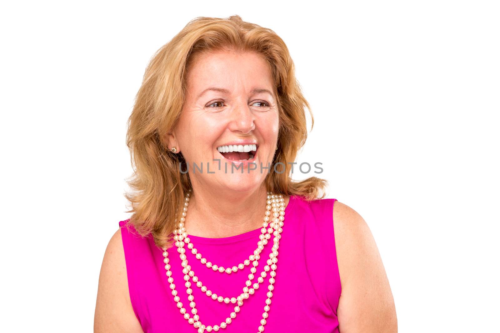 Mature Blonde Lady with large smile, she is wearing catchy pink shirt and pearl necklace