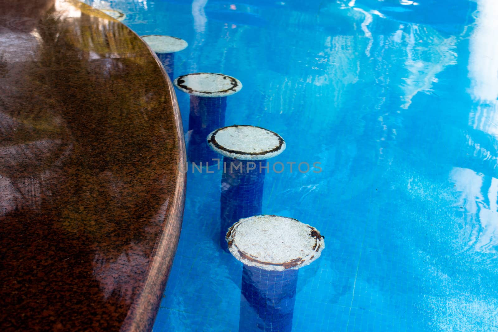 White bar seats in the swimming pool, rusty irons coming out from the seats giving authentic look, horizontal