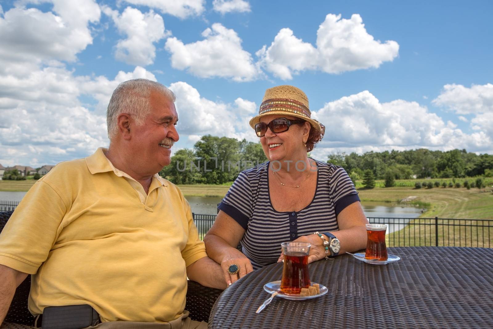 Senior Couple having Turkish tea at their pattio while holding their hands and looking at each other happily