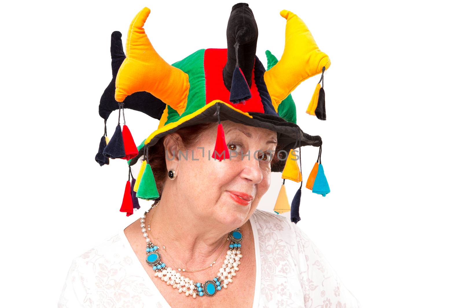 Mischievous senior lady similing to camera happily and mischievously with Jesters hat