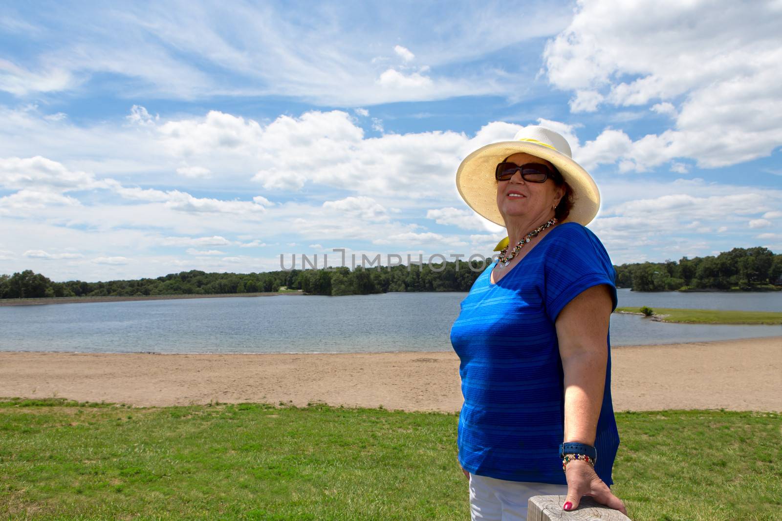 Matured woman standing on a Greenfield over the blue sky background