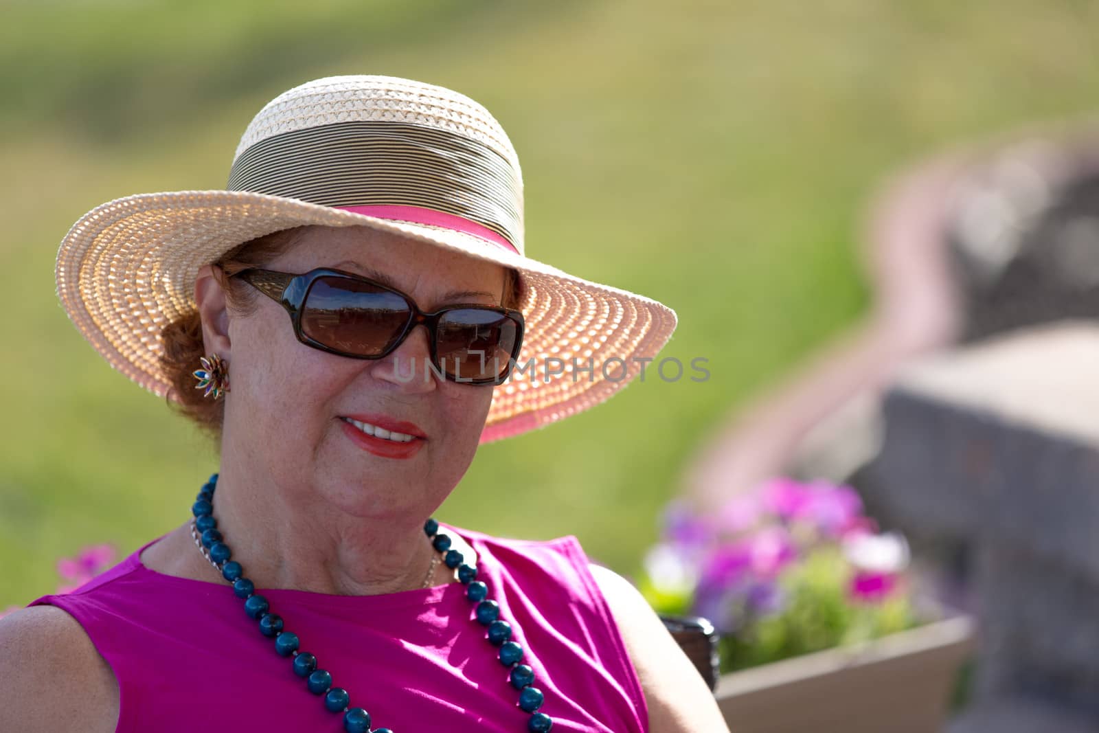 Woman with her straw hat looking at camera behind her sunglasses.