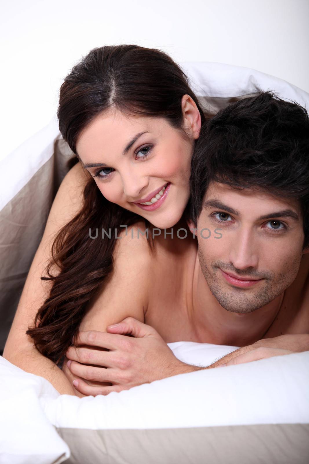 couple in bed embracing by phovoir