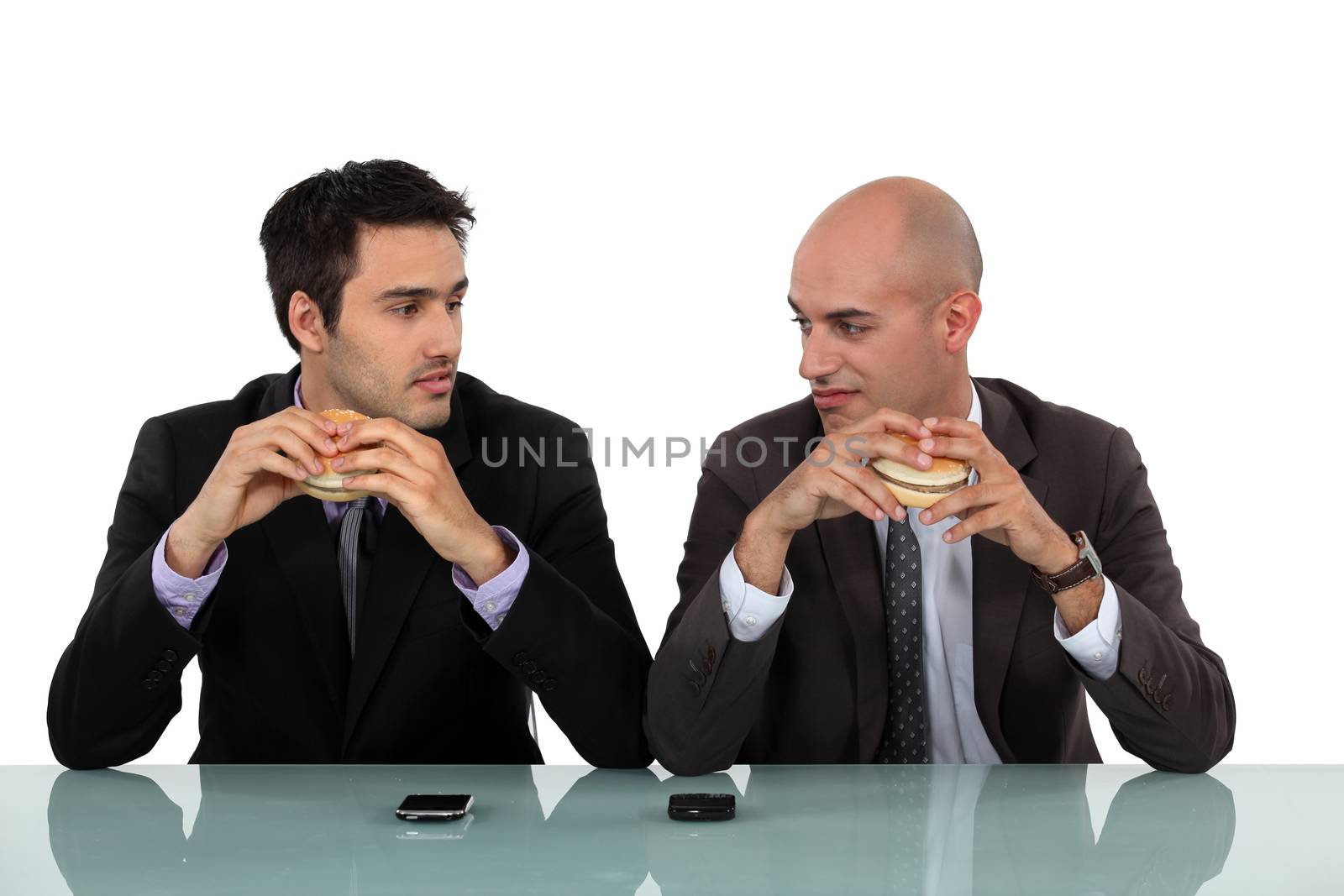 Two businessmen sat eating hanburgers