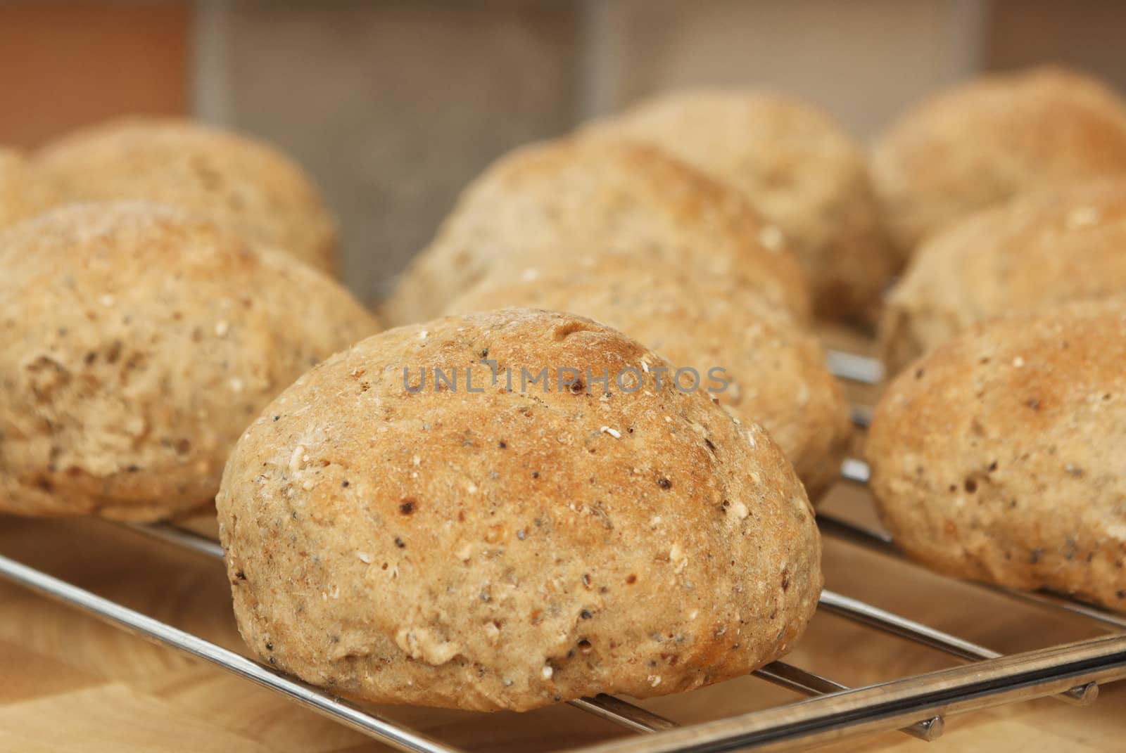 Close up of home made wholemeal bread rolls fresh from the oven, cooling on a wire rack, in a domestic kitchen setting