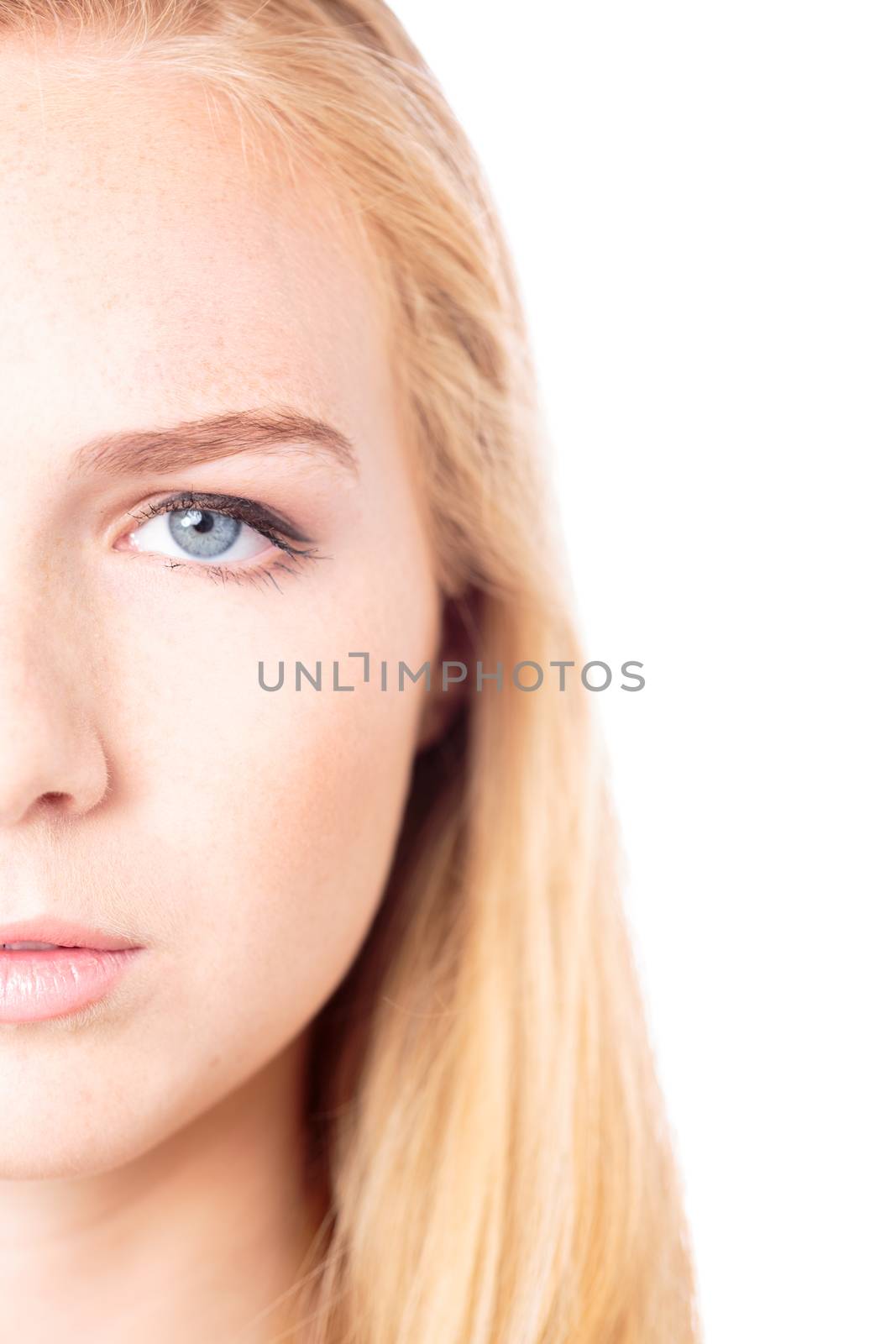 Half face closeup portrait of the eye of an sttractive young woman with no makeup and a natural smooth complexion with long blond hair, isolated on white