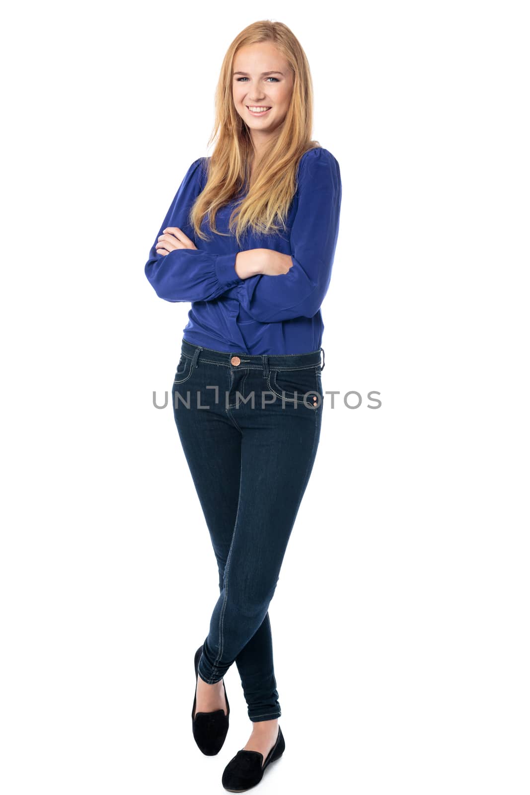 Happy confident relaxed young woman standing with crossed arms and legs smiling at the camera, isolated on white