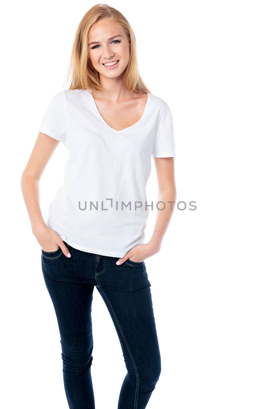 Beautiful relaxed casual young woman standing with her hands in the pockets of her jeans smiling at the camera, three quarter body on white