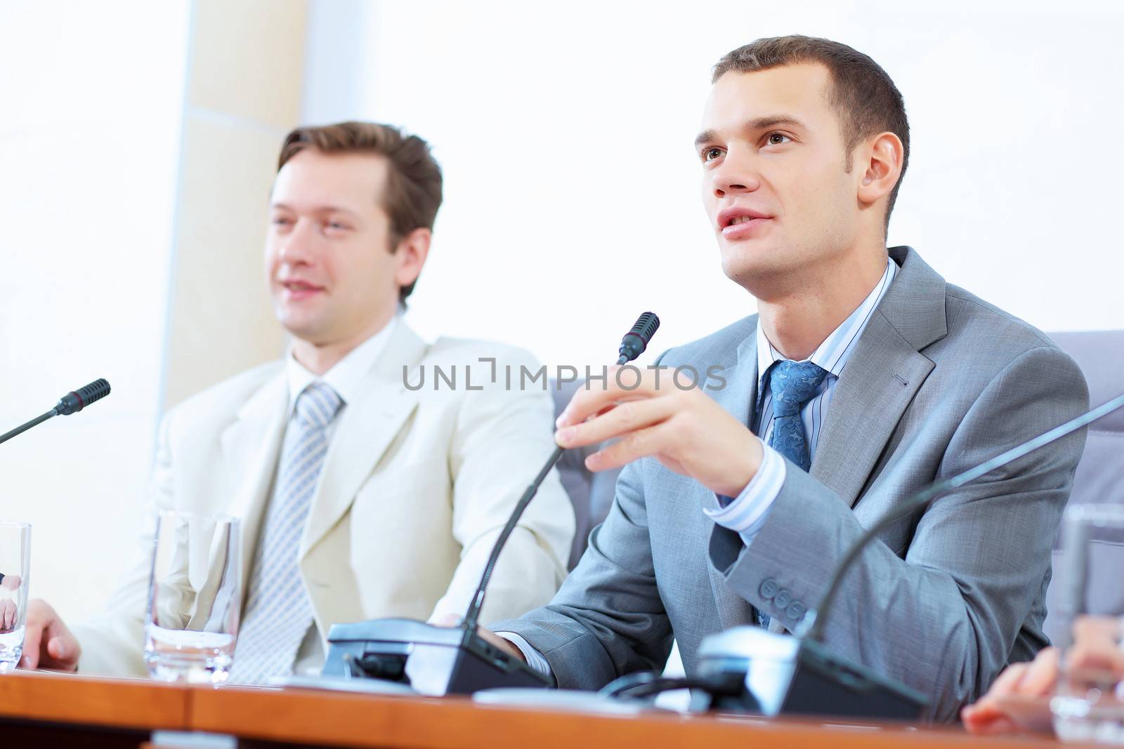 Image of two businessmen sitting at table at conference