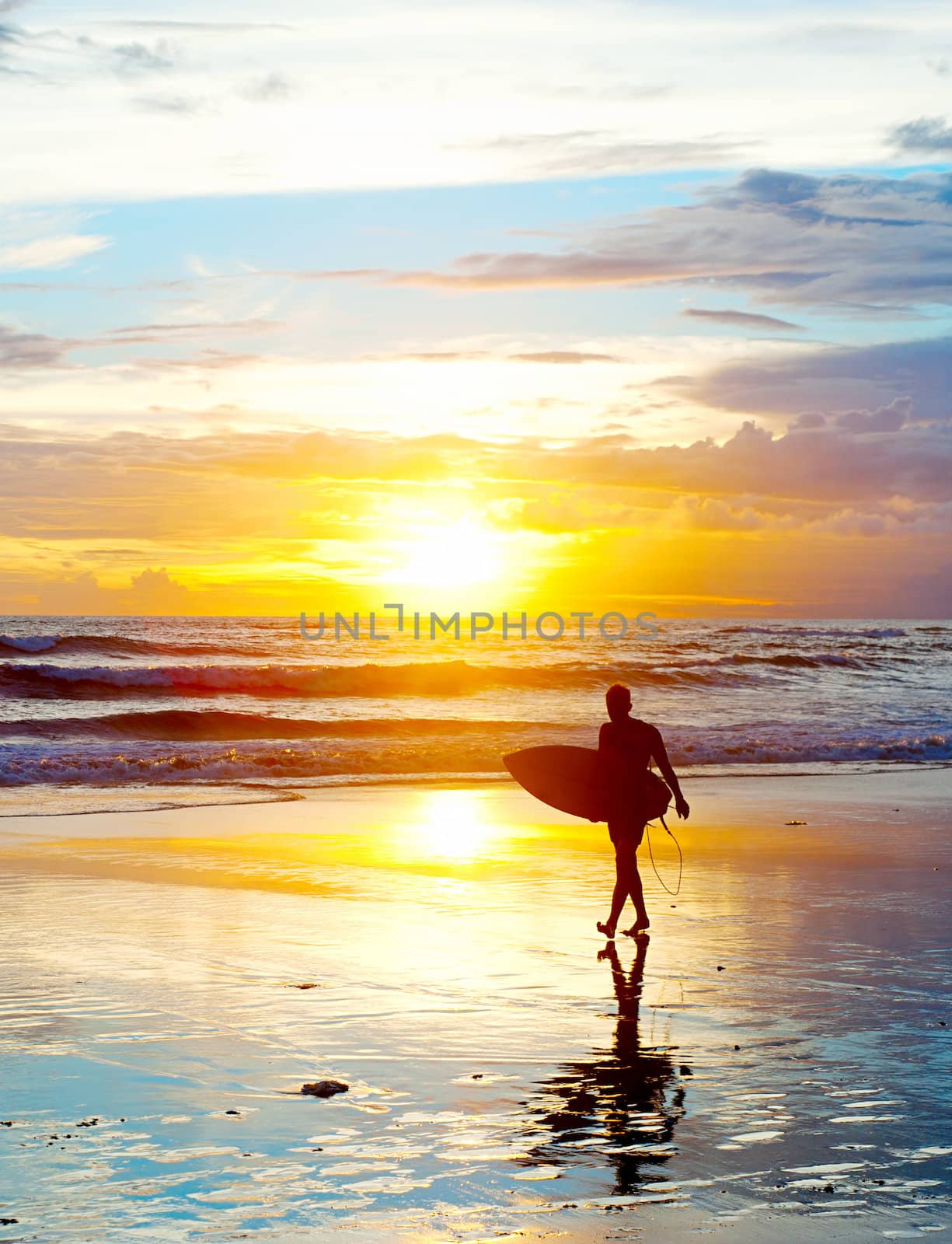 Surfer on the ocean beach at sunset on Bali island, Indonesia