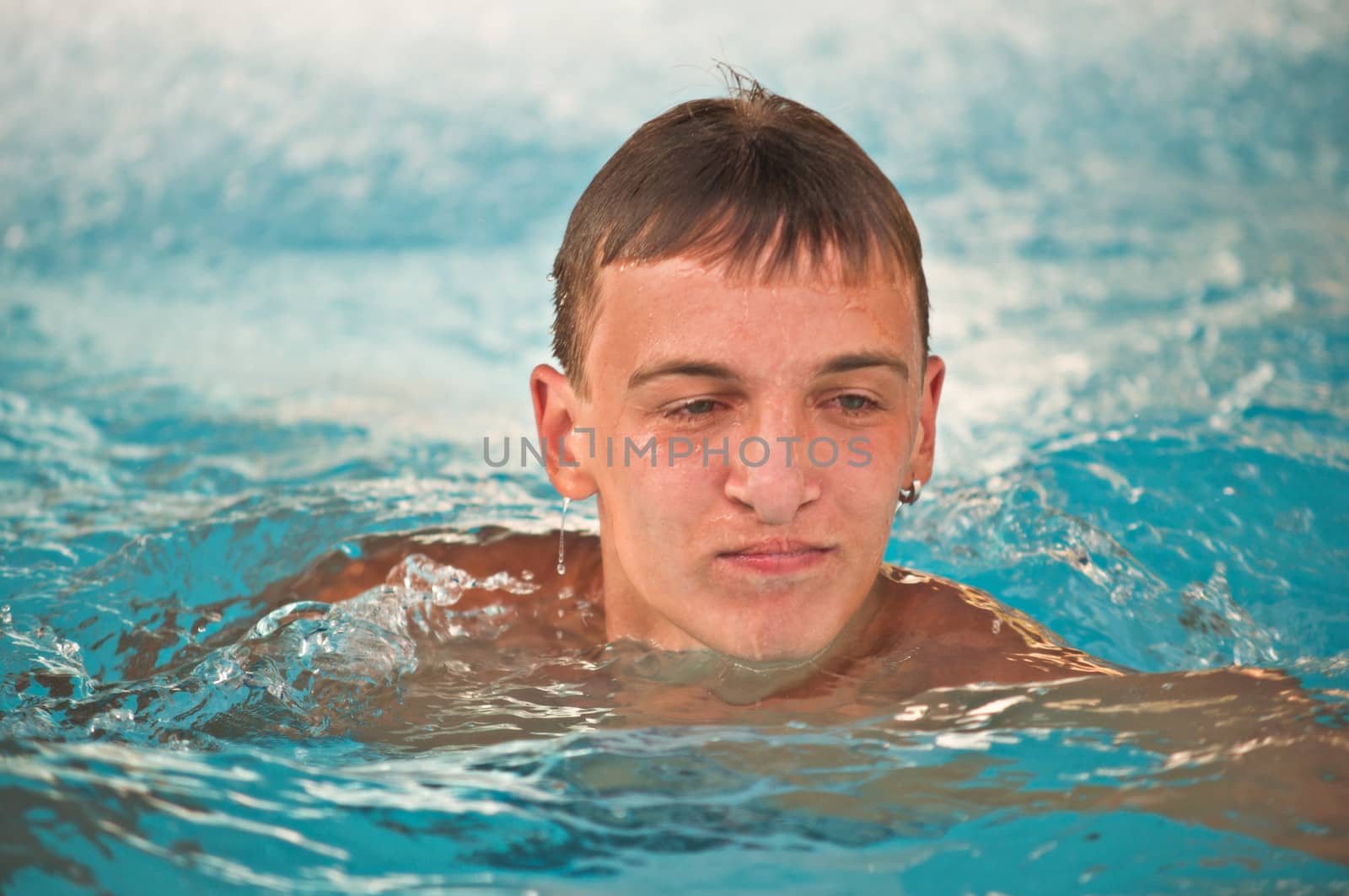 happy teen boy in blue swimming pool portrait  by LarisaP