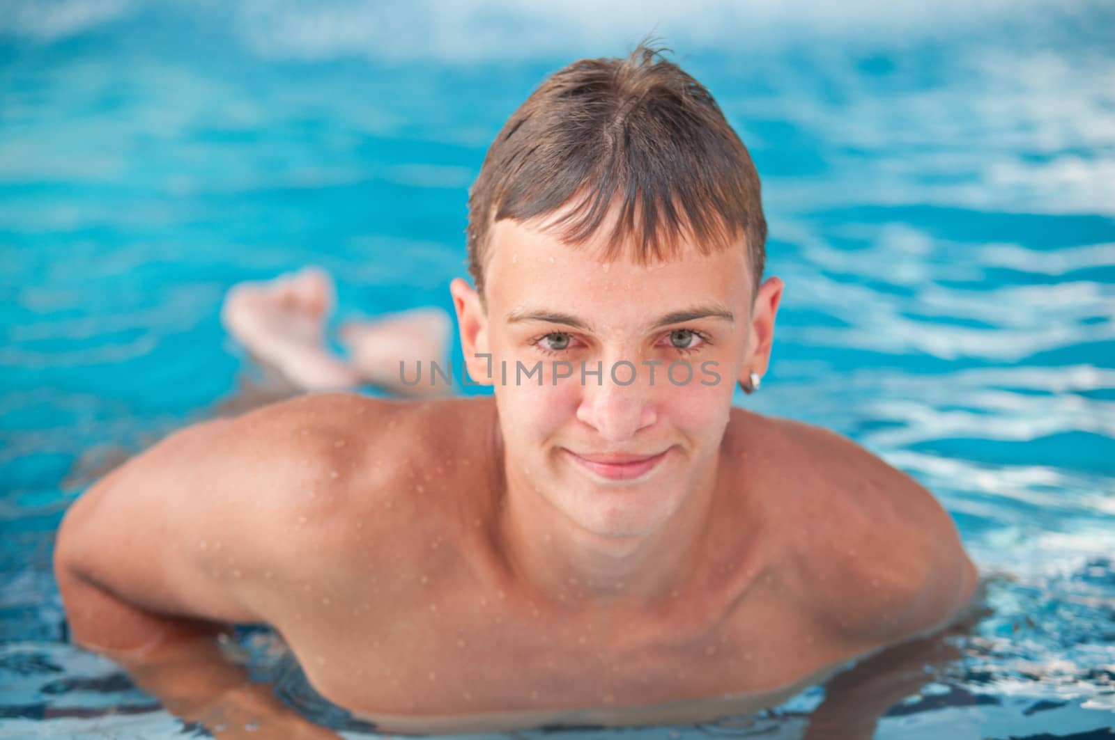 happy teen boy in blue swimming pool portrait  by LarisaP