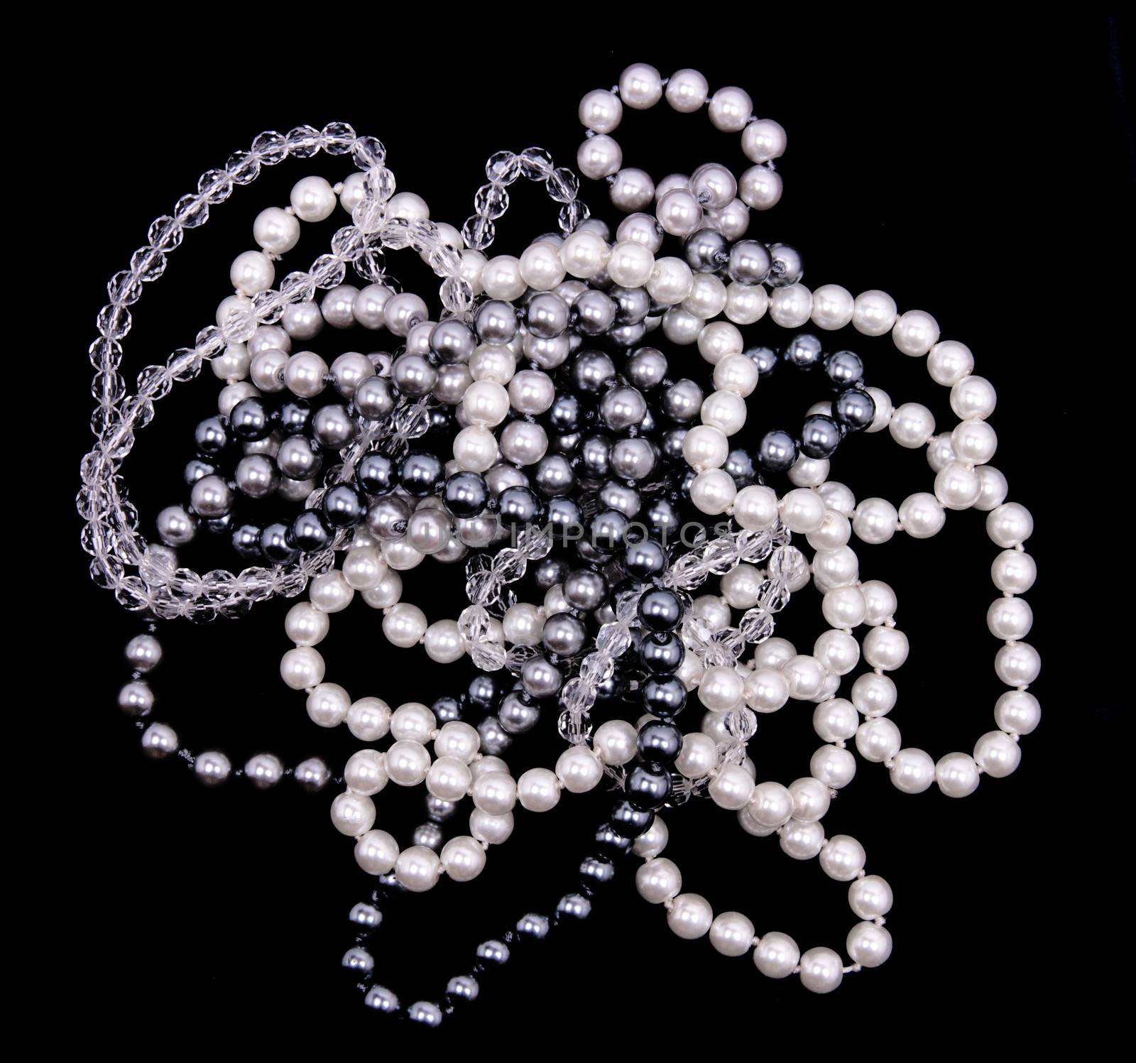 White, black and grey pearls on the black silk background 