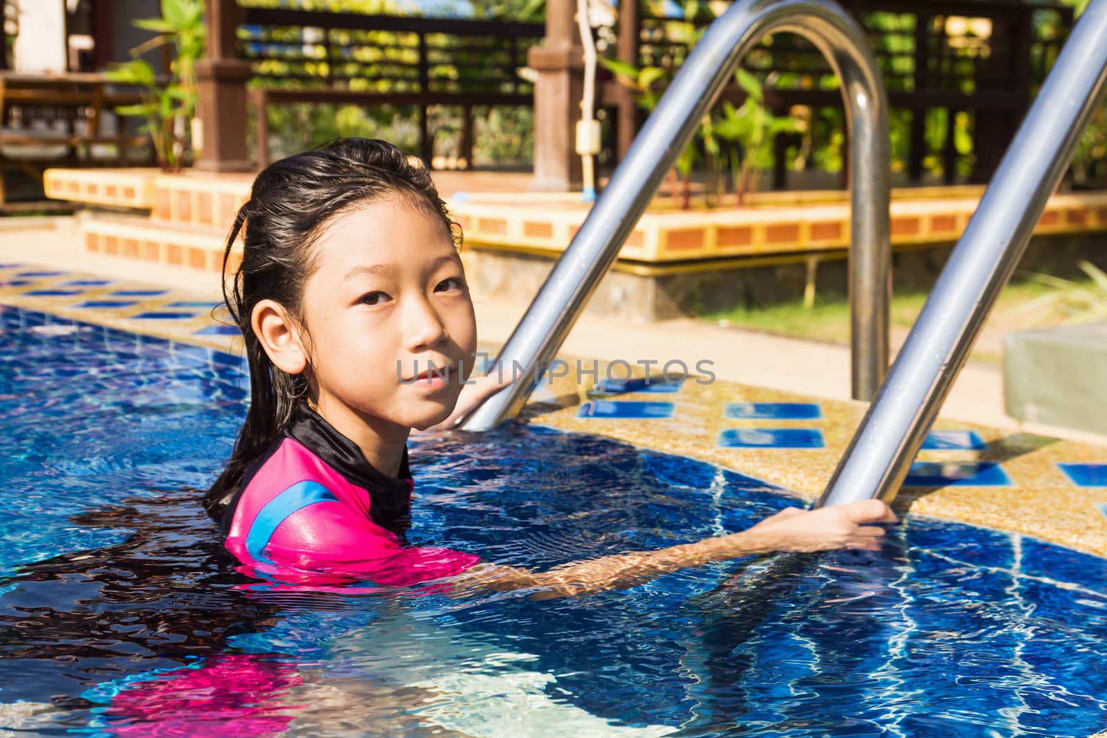 Girl relaxing on the side of a swimming pool