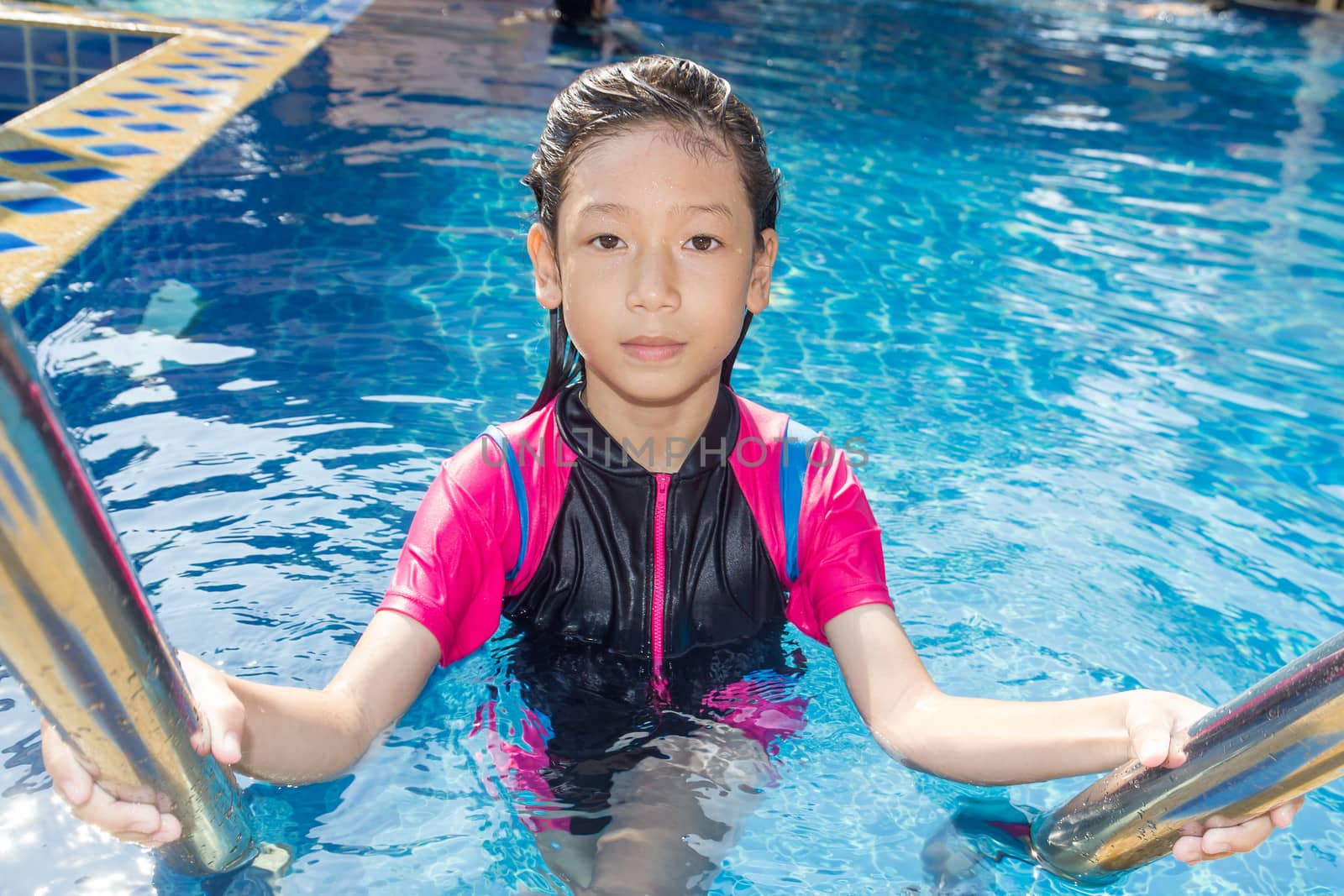 Girl relaxing on the side of a swimming pool