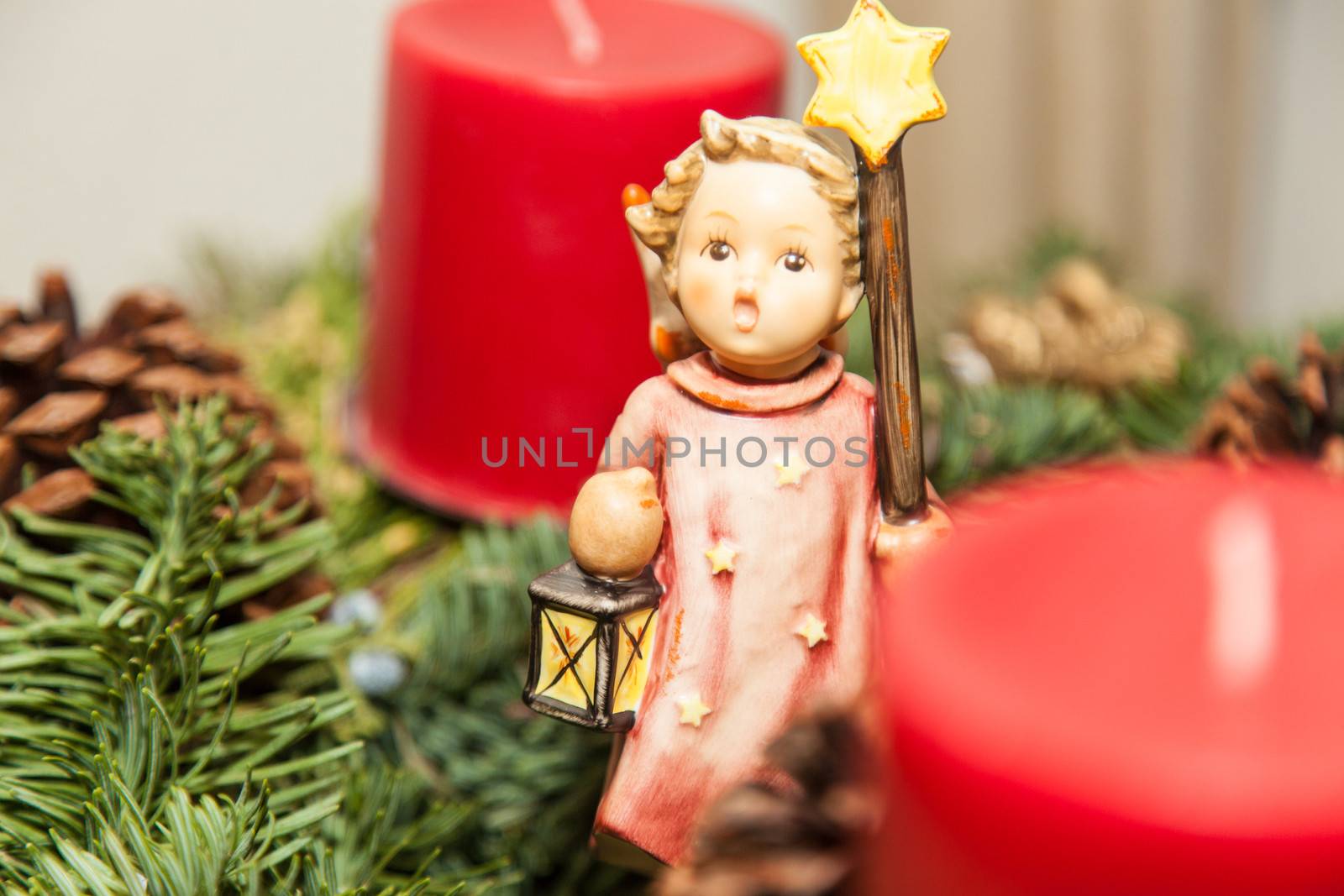 Christmas decorations with angel and red candles on tree branch.