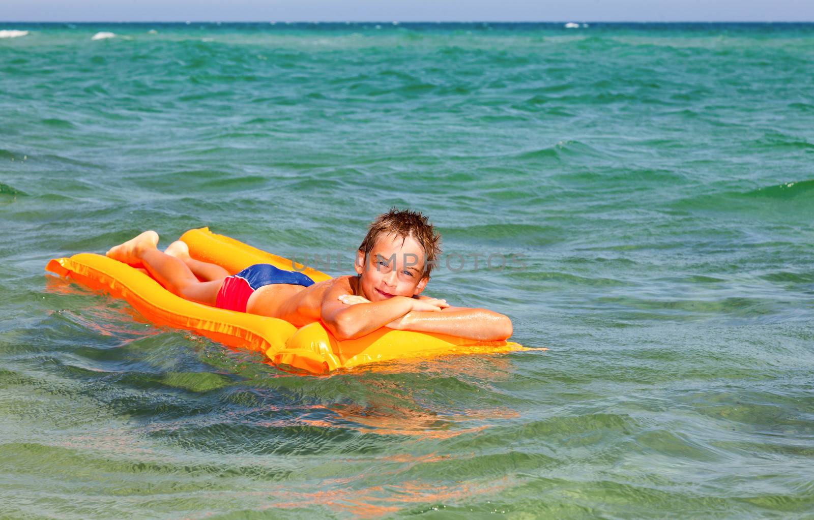 Happy boy enjoying summer day floating in the sea