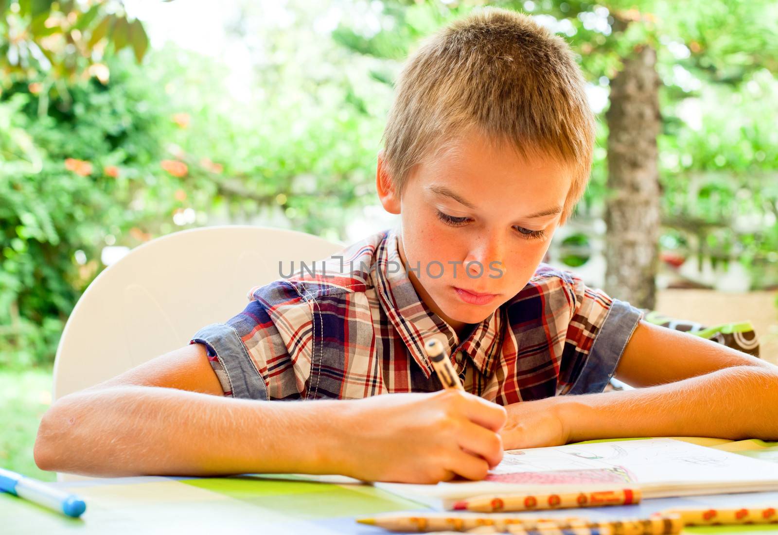 Scoolboy sitting at table drawing