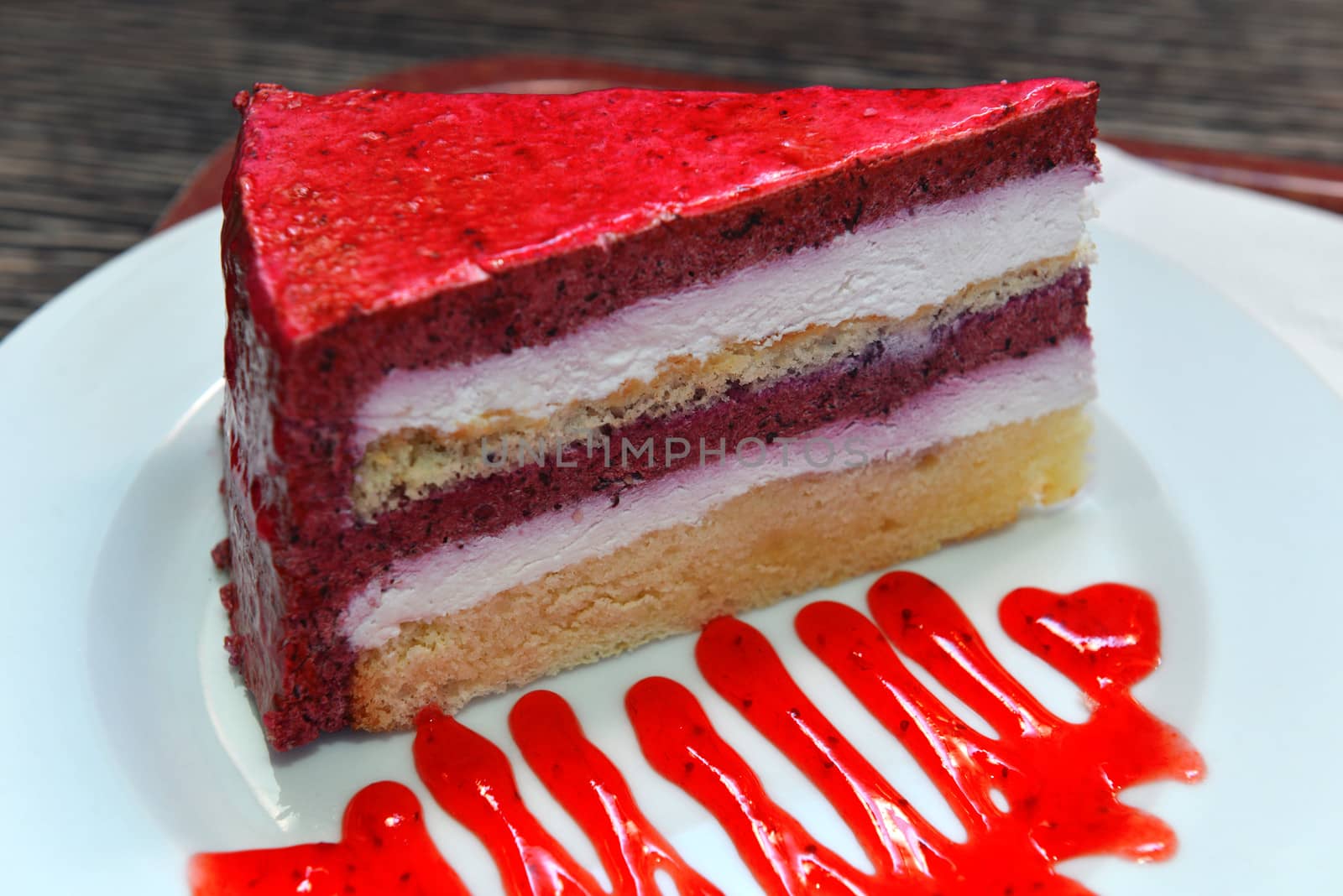 A piece of tasty cake made of berries with jam on the plate