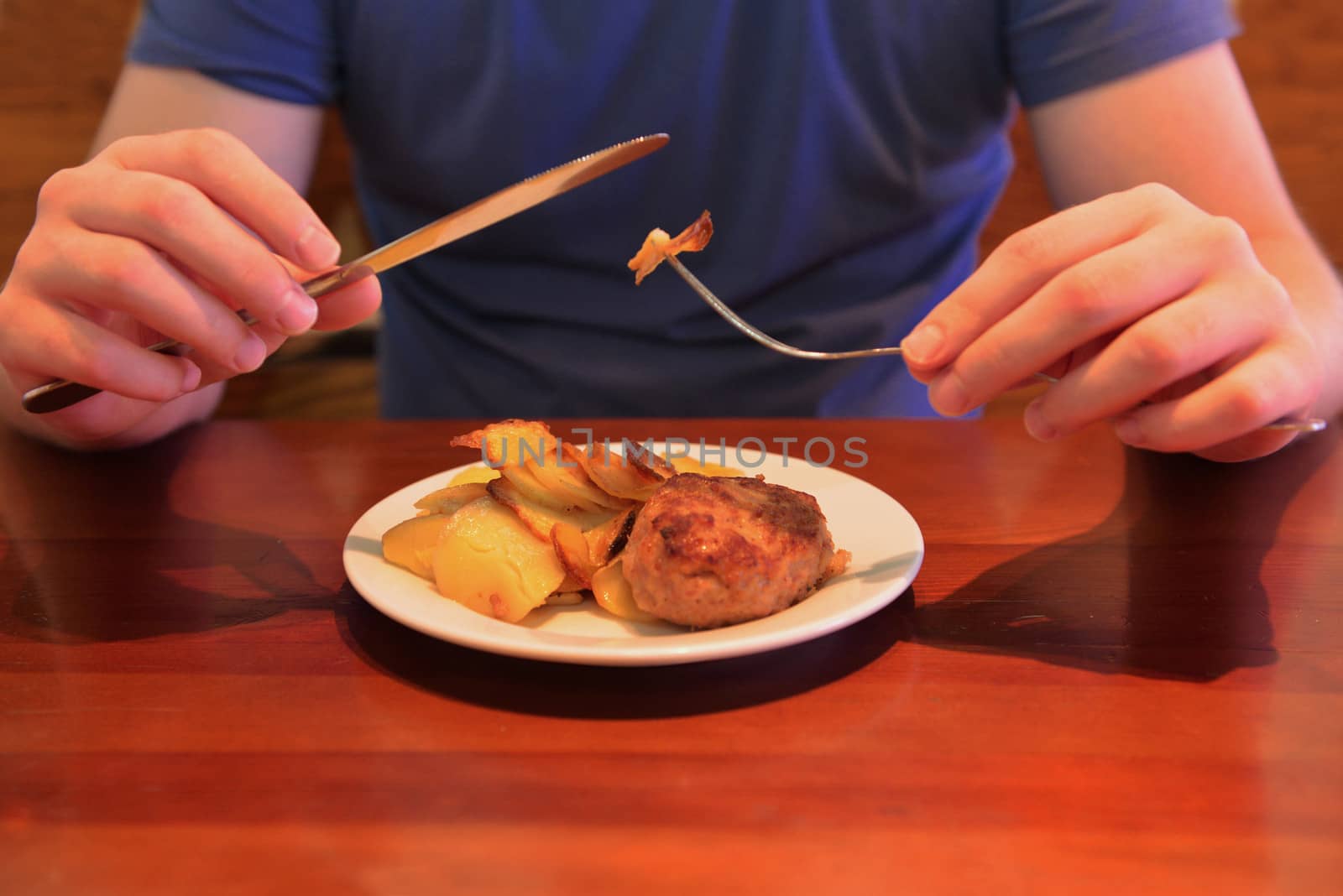 Man eating fried potatoes and cutlet