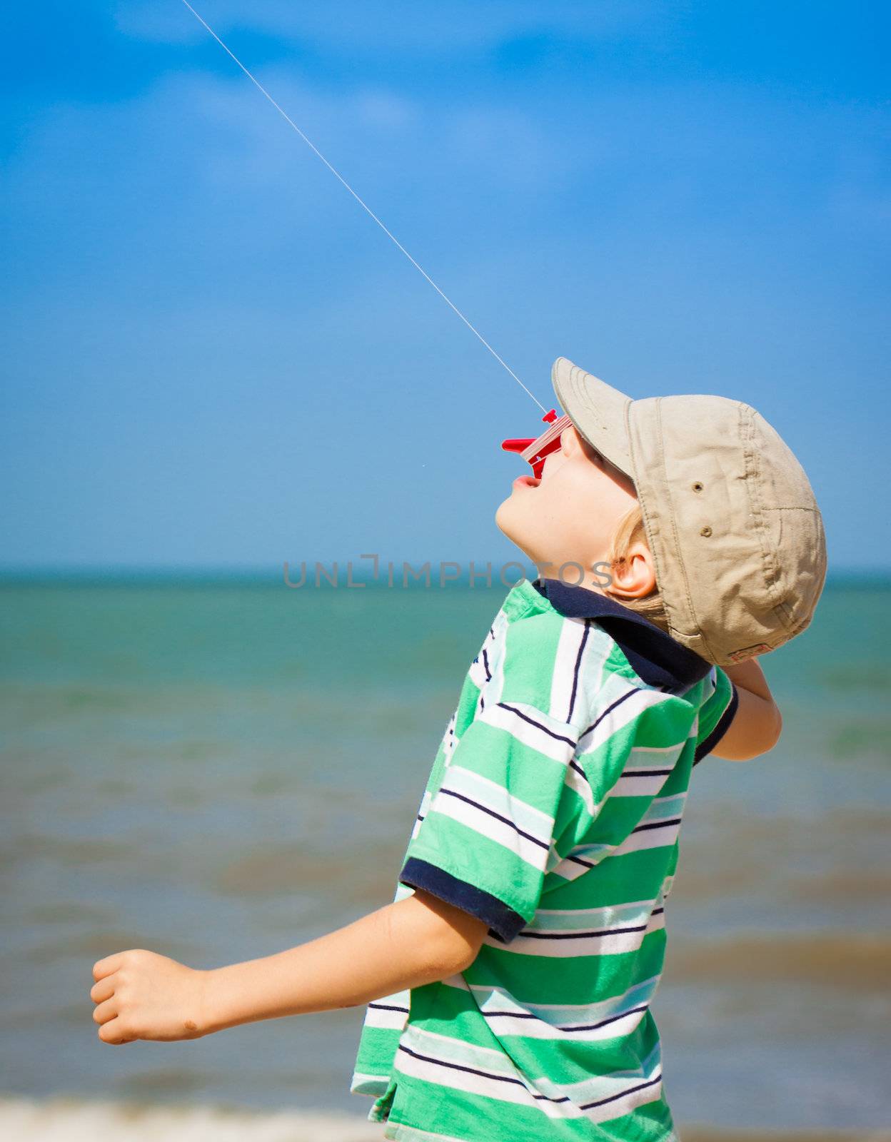 A boy flying a kite at the beach.
