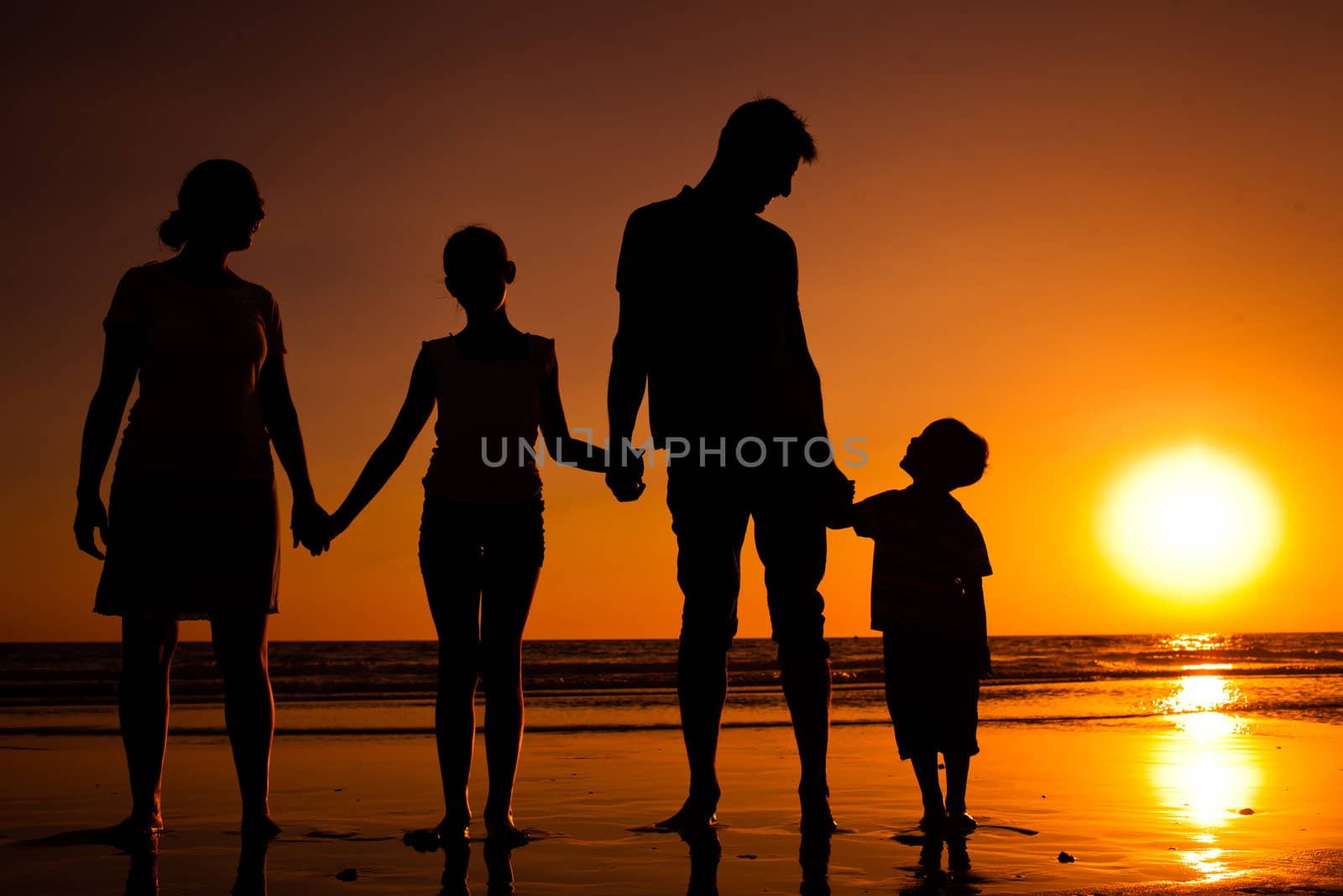 Silhouette of family on the beach at sunset