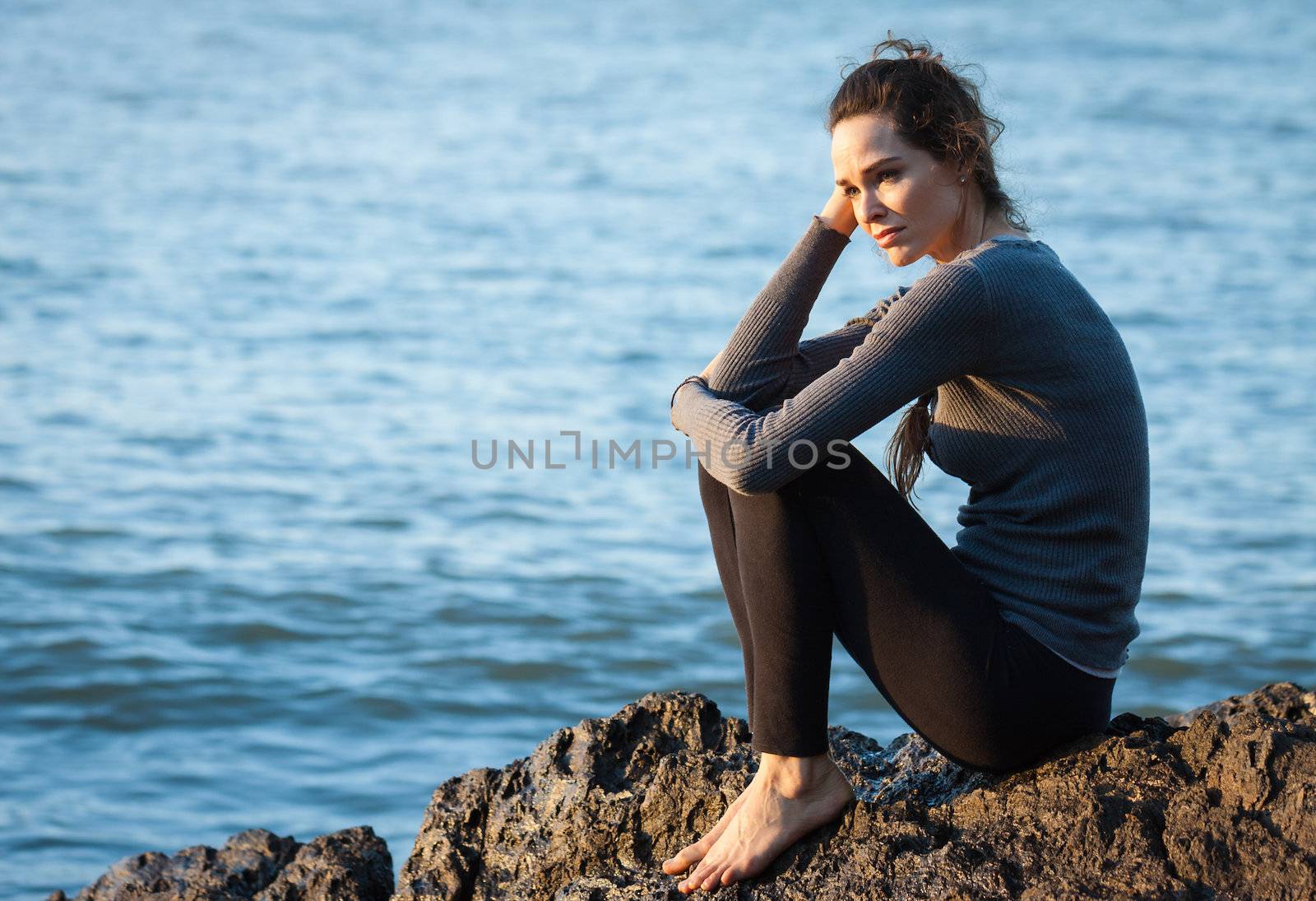 Sad and depressed woman sitting by the ocean