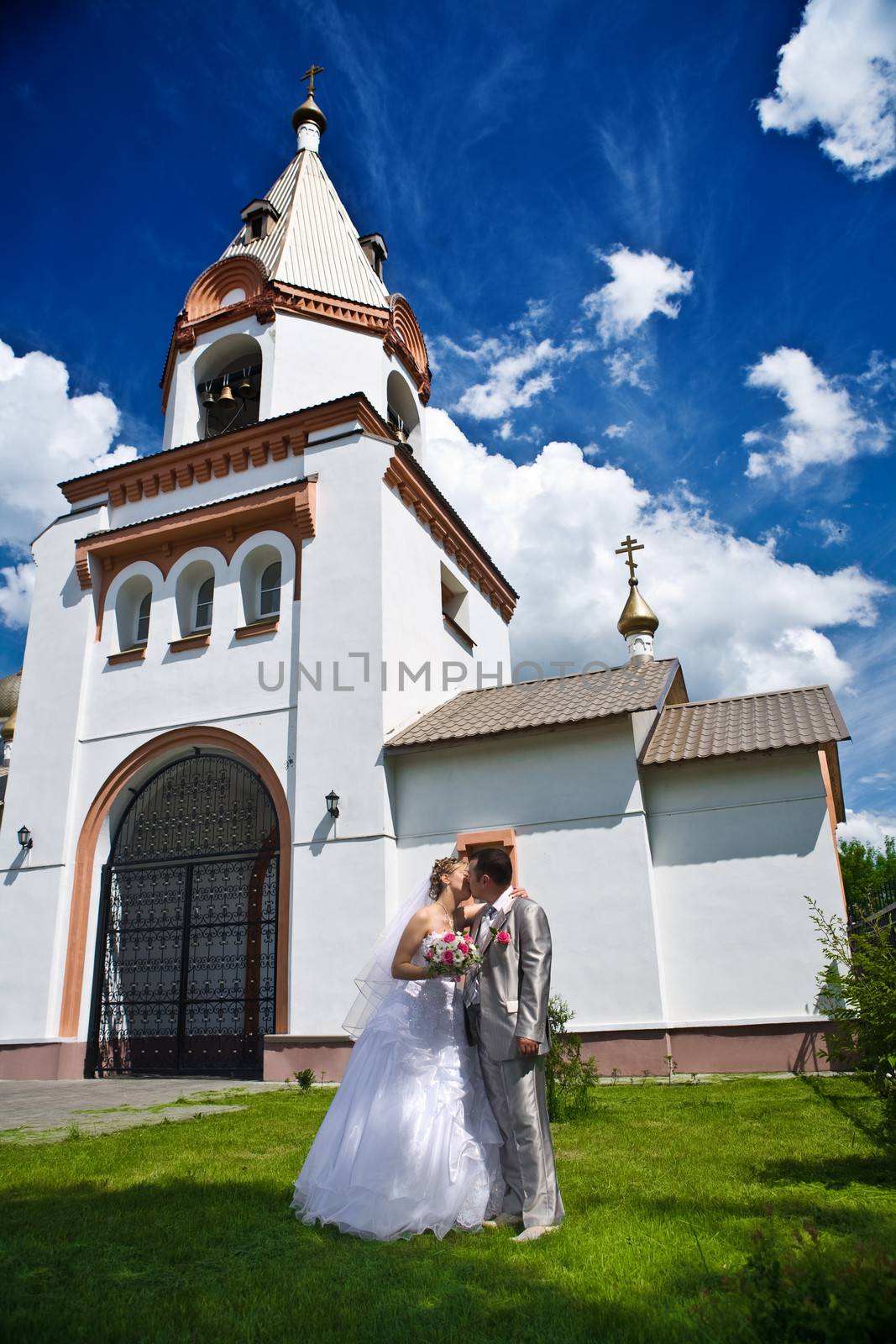 Newly married kiss on a background of church