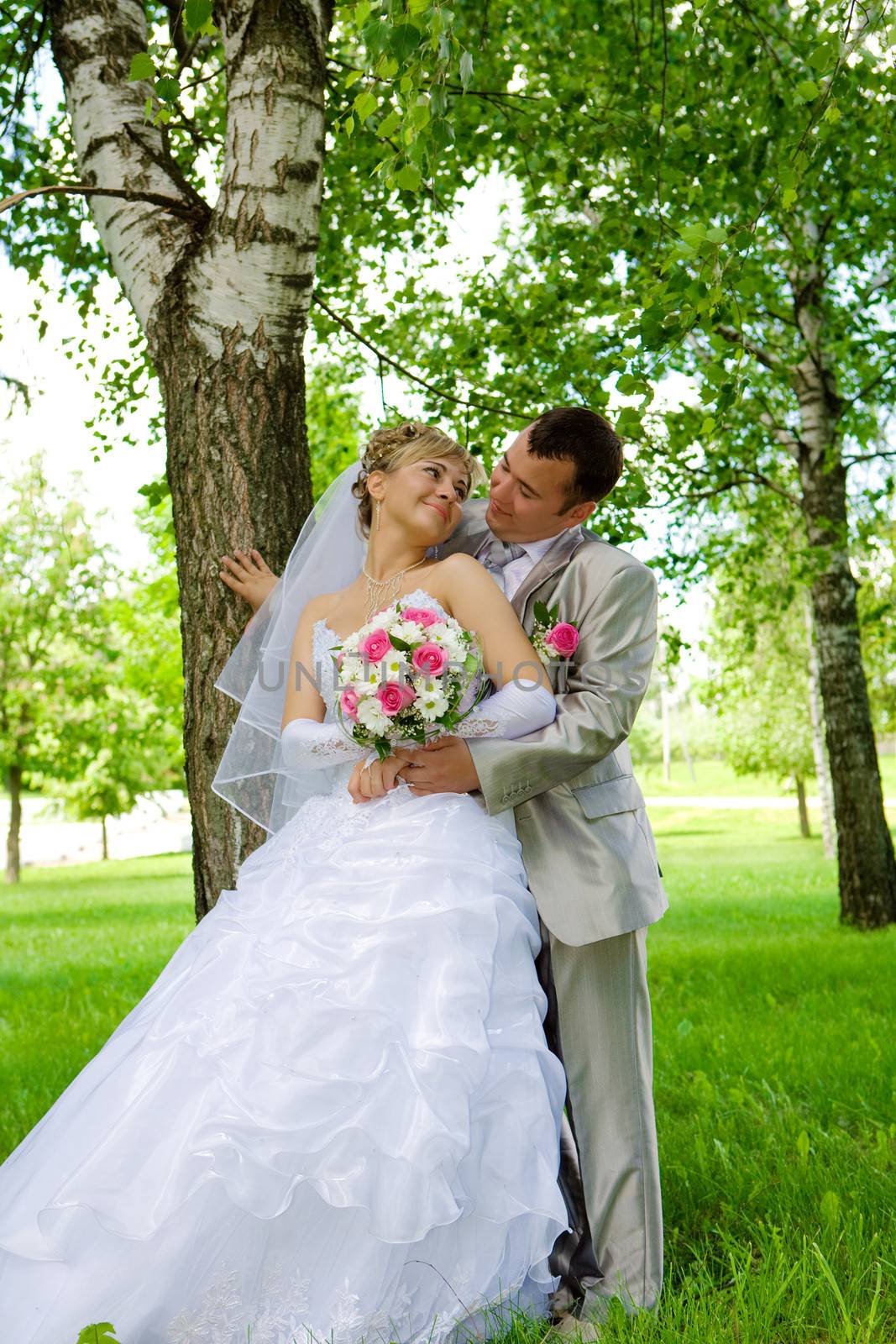 The groom and the bride in park near a tree by mihalec