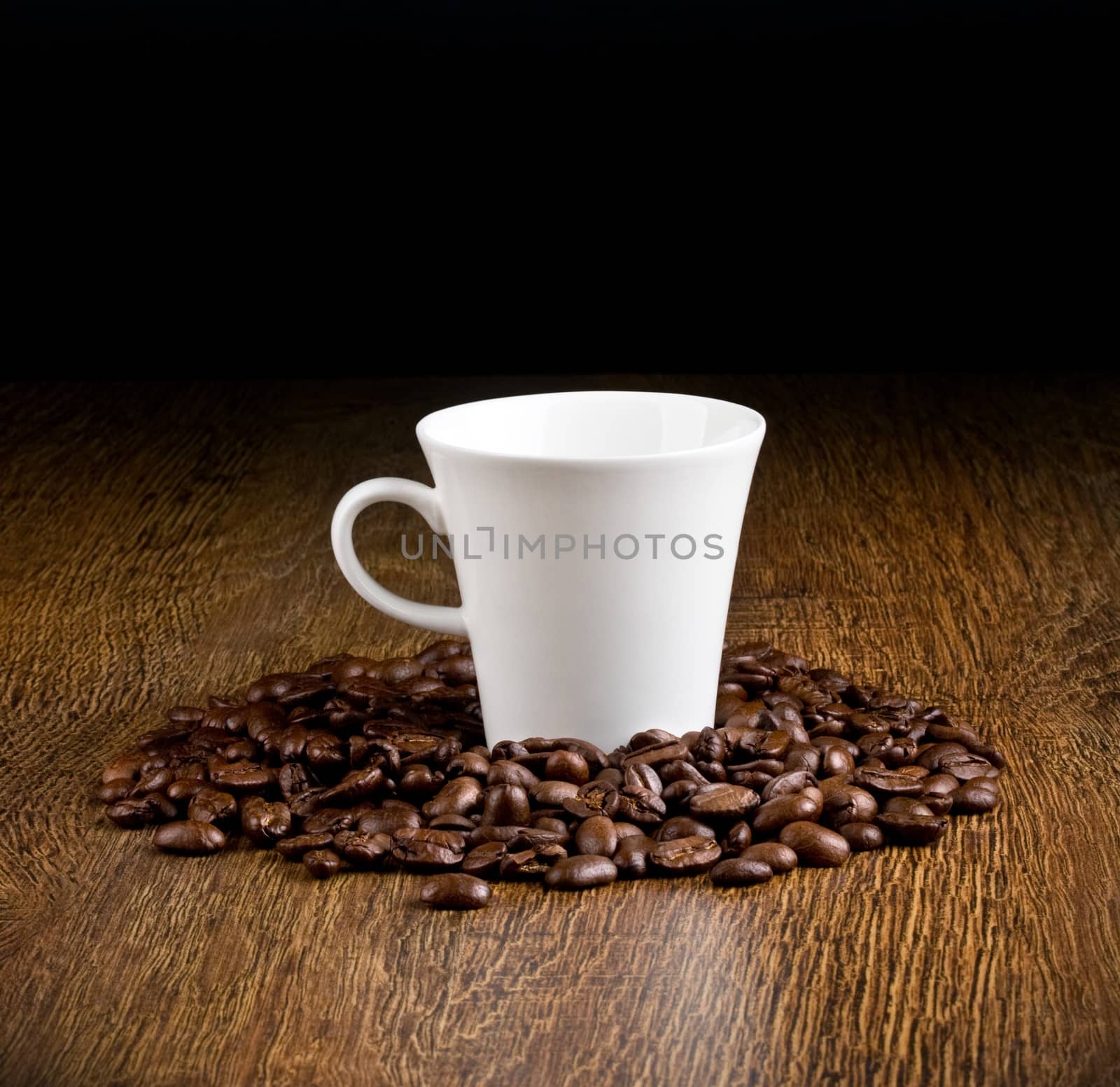 Cup of coffee on a wooden table in surrounded by coffee beans