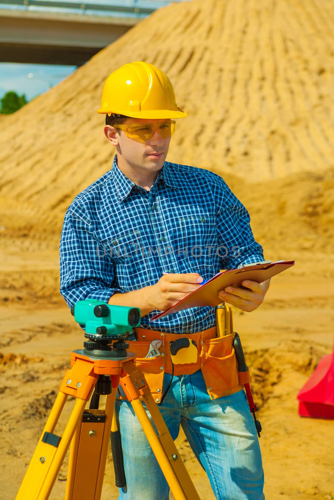 a contractor with theodolite writing in clipboard by mihalec