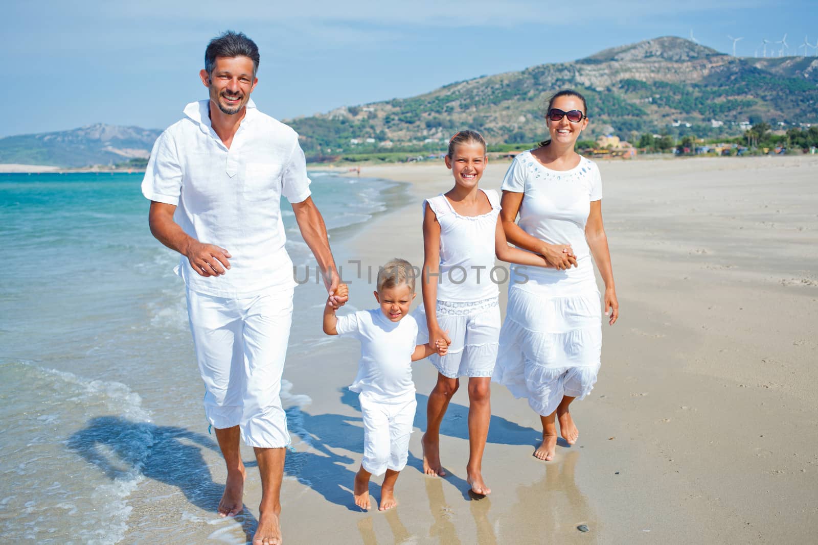 Photo of happy family running down the beach on summer