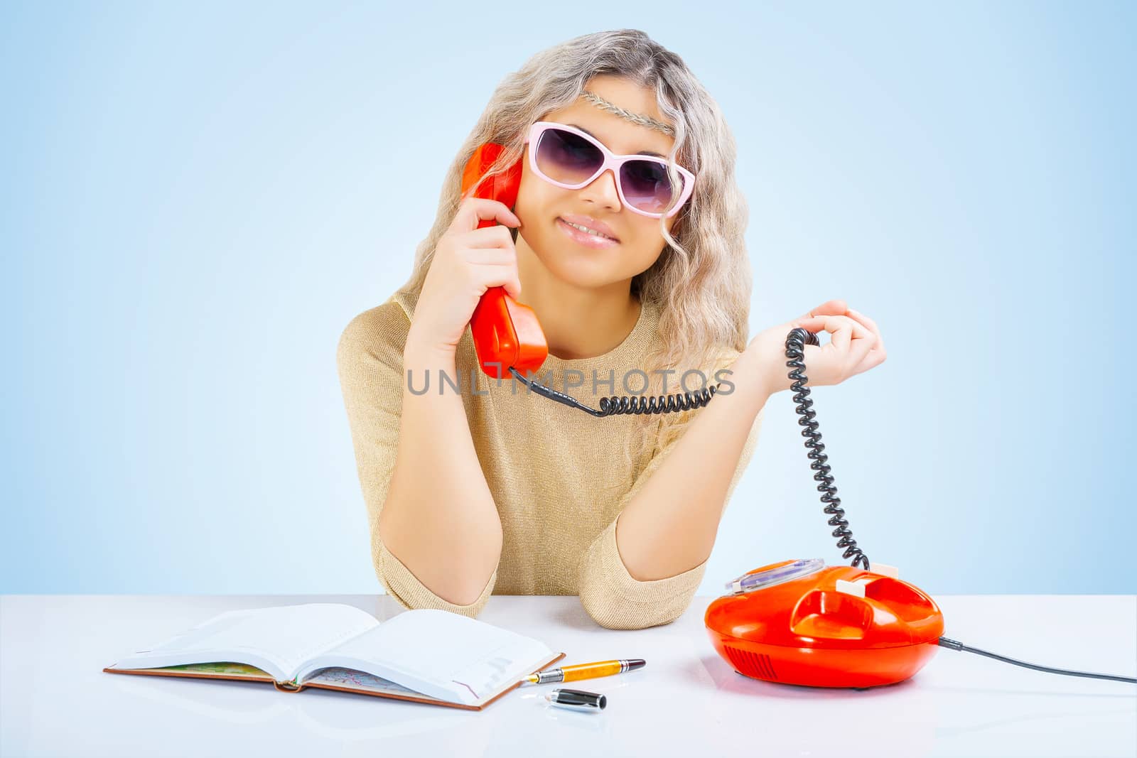 a young blonde at table with telephone