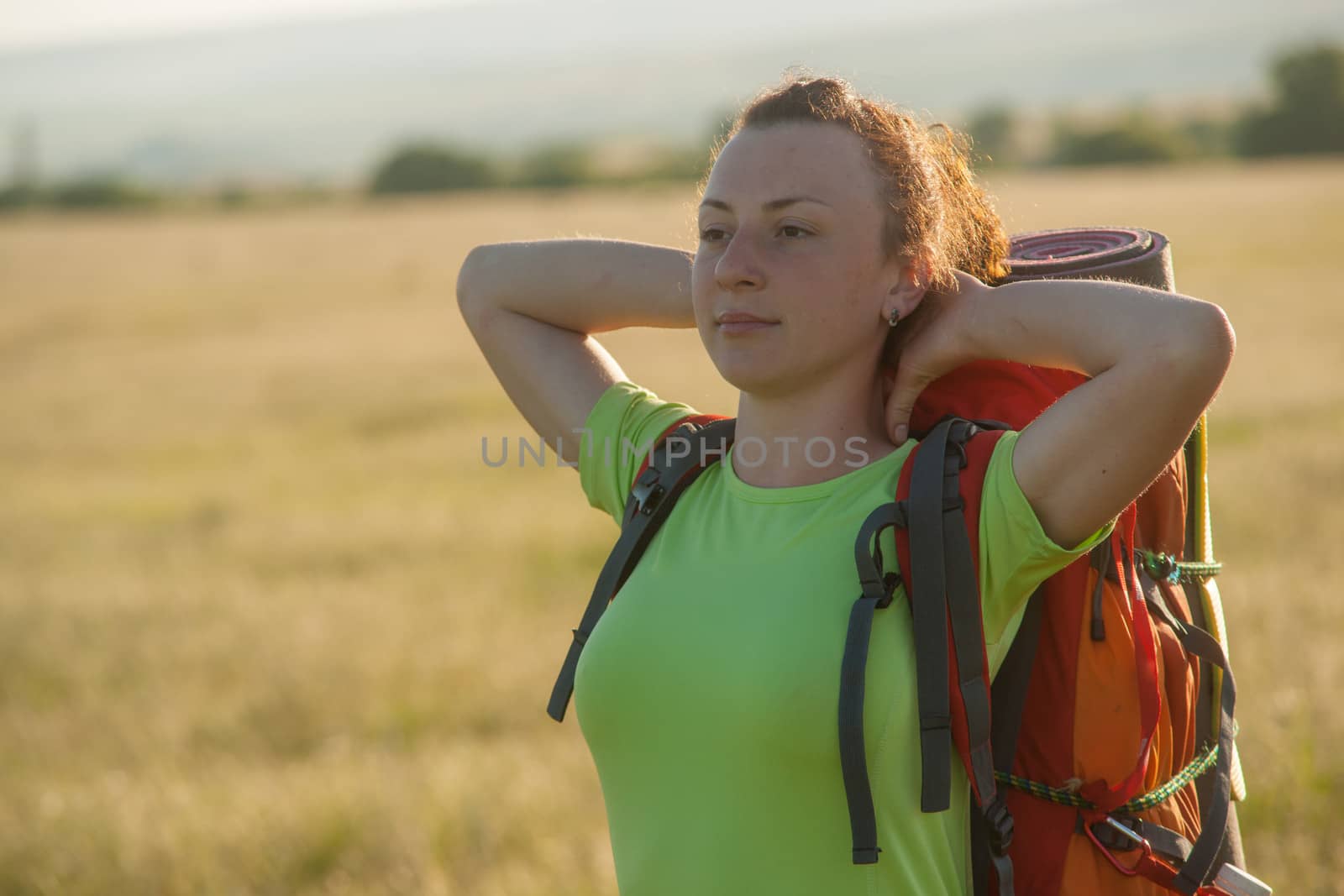 Happy smiling woman in field. Green grass in foreground and clear sky in background.