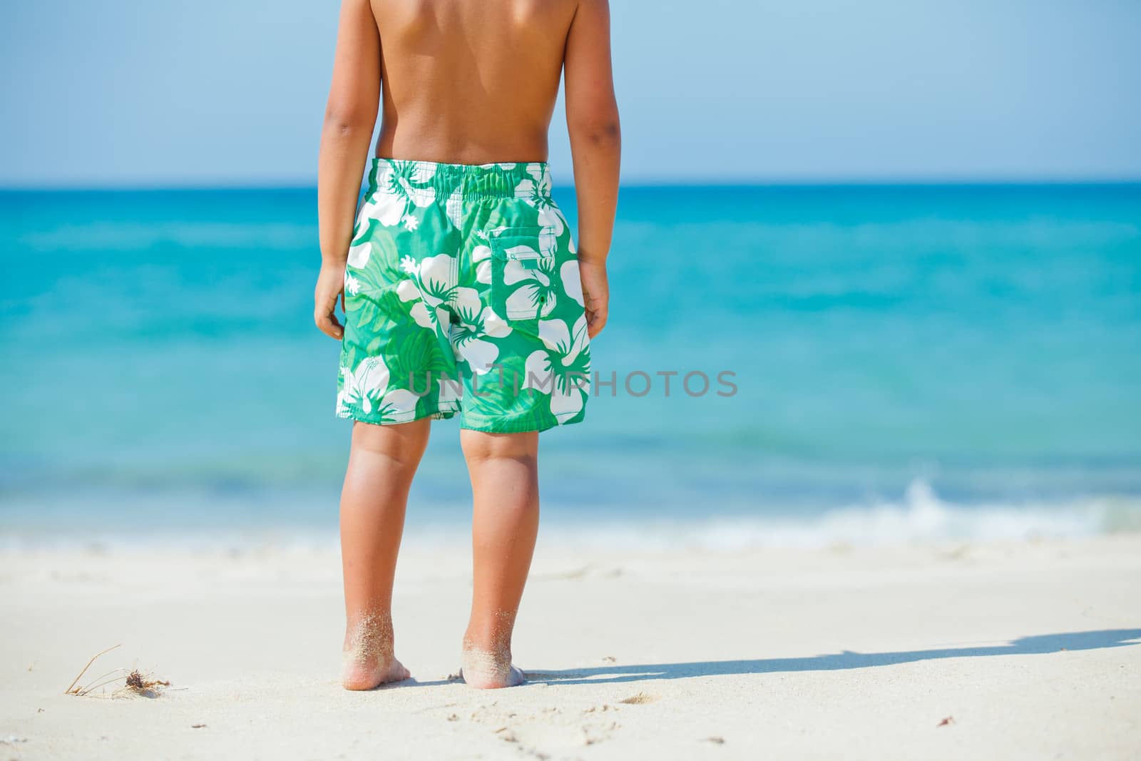 Walking on the beach. Close up on boy legs walking along the sea side.