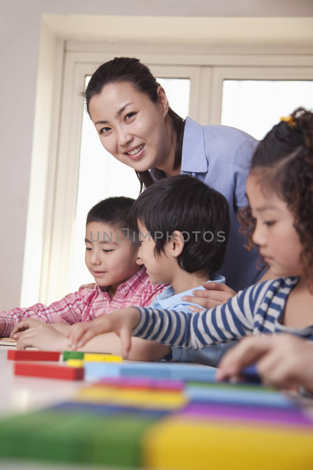 Teacher Helping Her Students and Looking at Camera by XiXinXing
