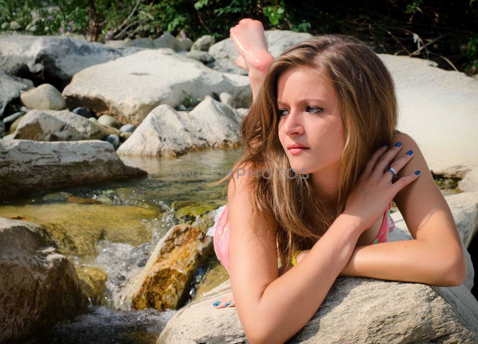 Pretty brunette girl in bikini laying on rocks by artofphoto