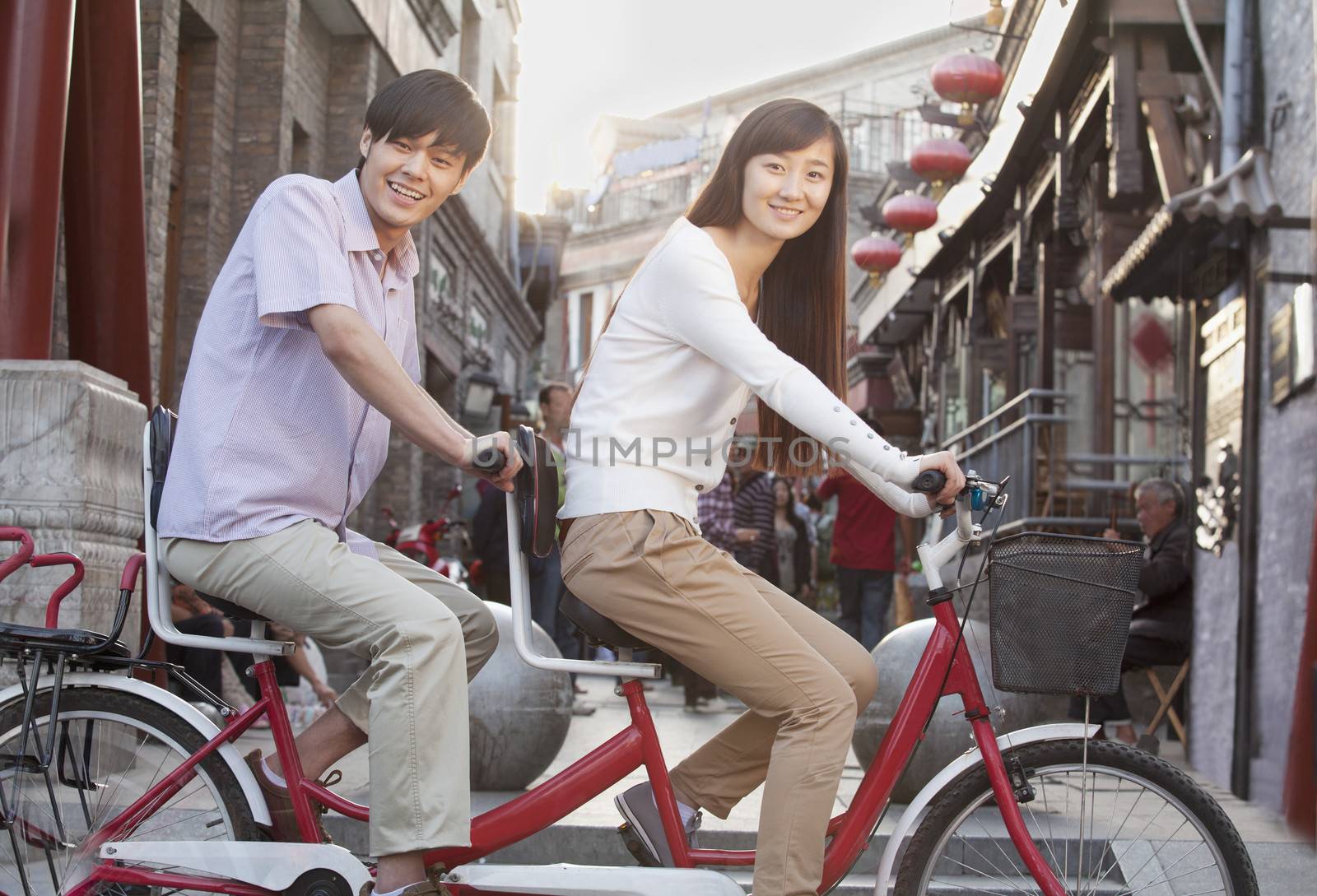 Side View of Young Heterosexual Couple on a Tandem Bicycle in Beijing Looking at Camera