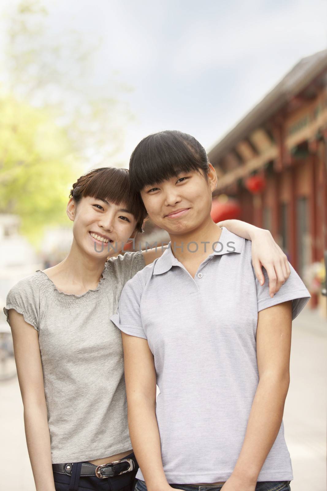 Women smiling and embracing outdoors  by XiXinXing