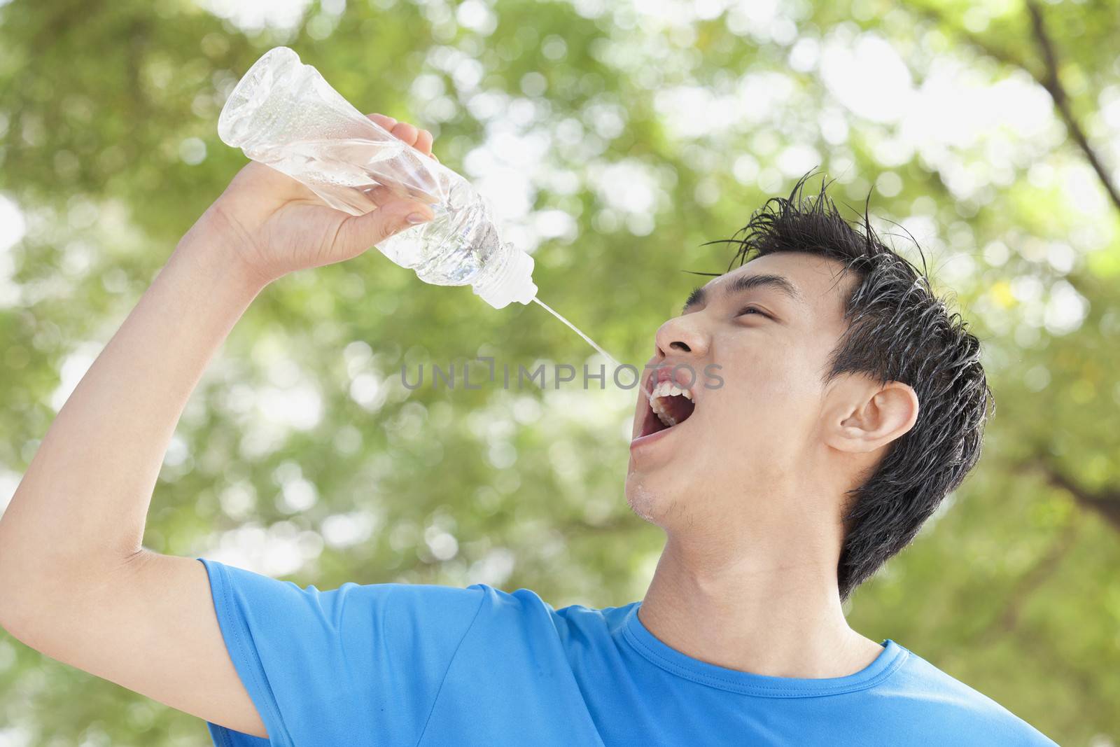 Young Man Drinking Bottled Water in Park