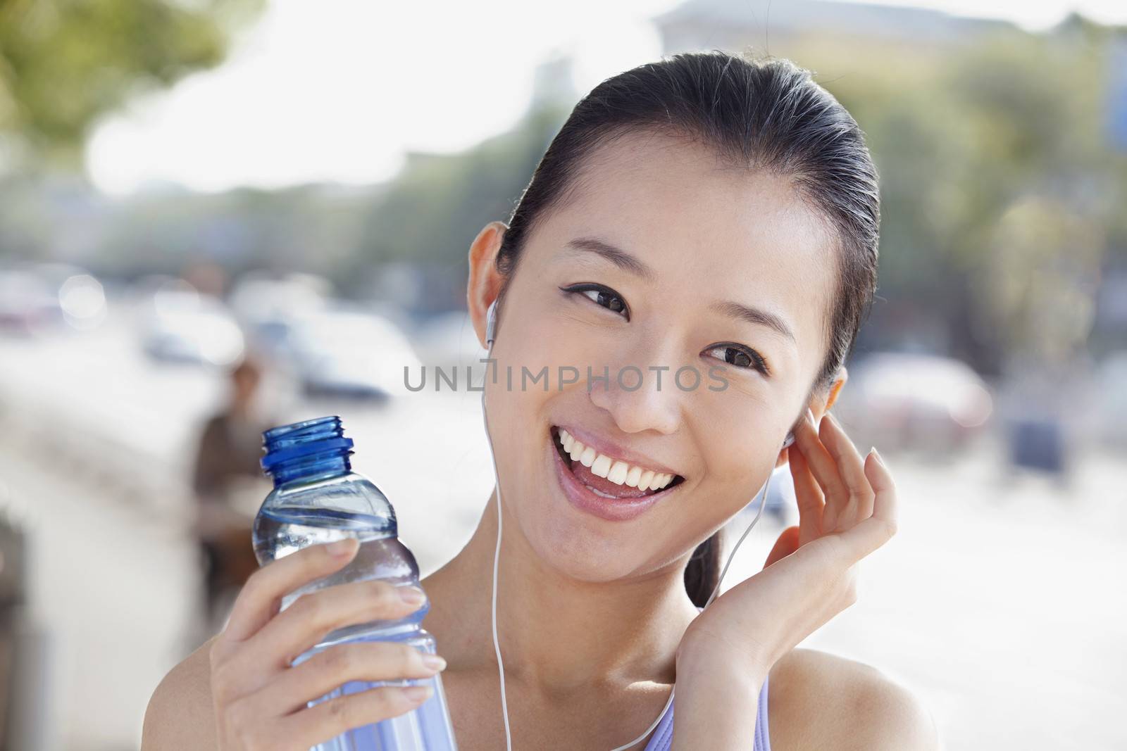 Young Woman with Bottled Water Listening to Music