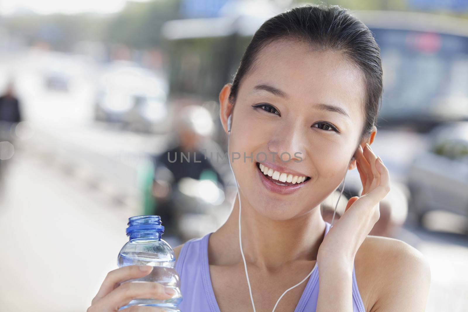 Young Woman with Bottled Water Listening to Music