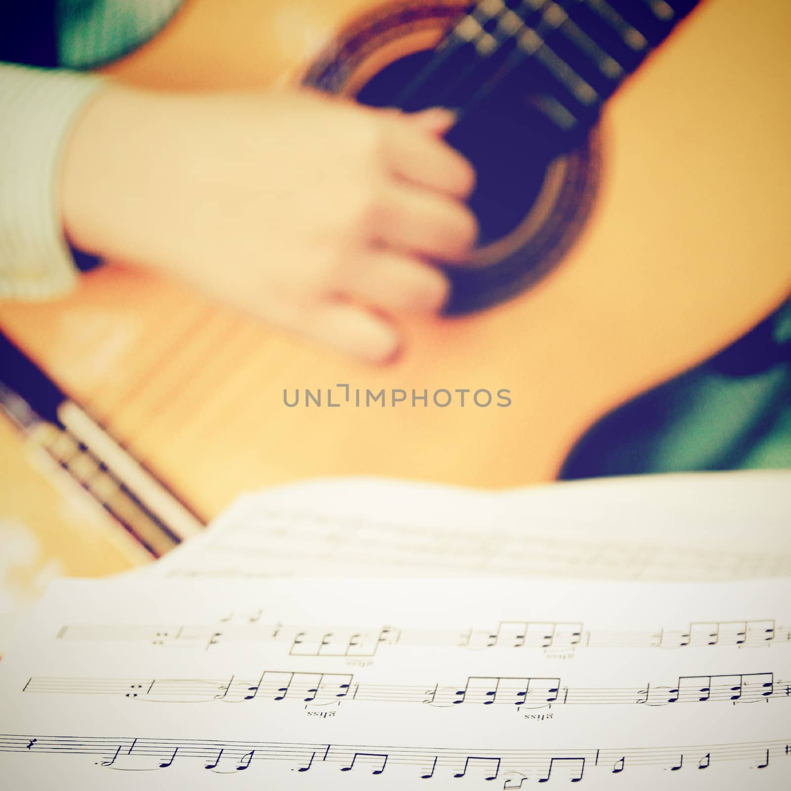 Musician playing classical guitar with musical chords, retro filter effect