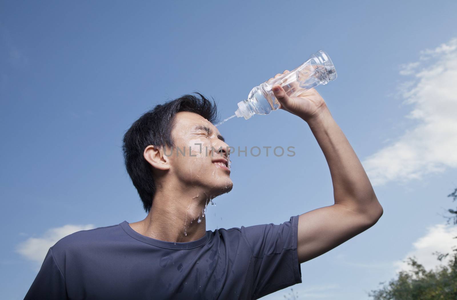 Young Man Pouring Bottled Water Over His Head