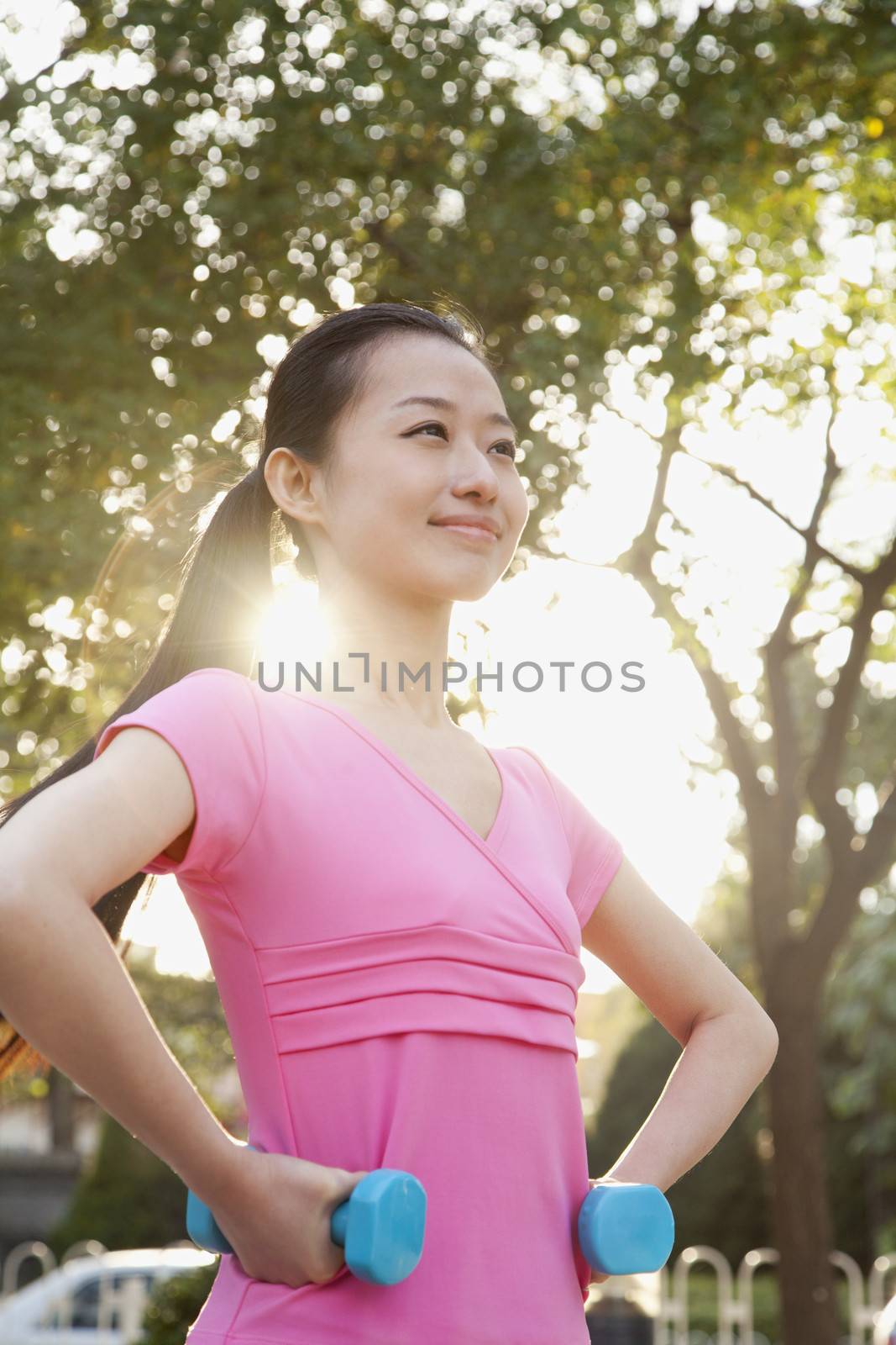 Young Woman Exercising in Park with Dumbells