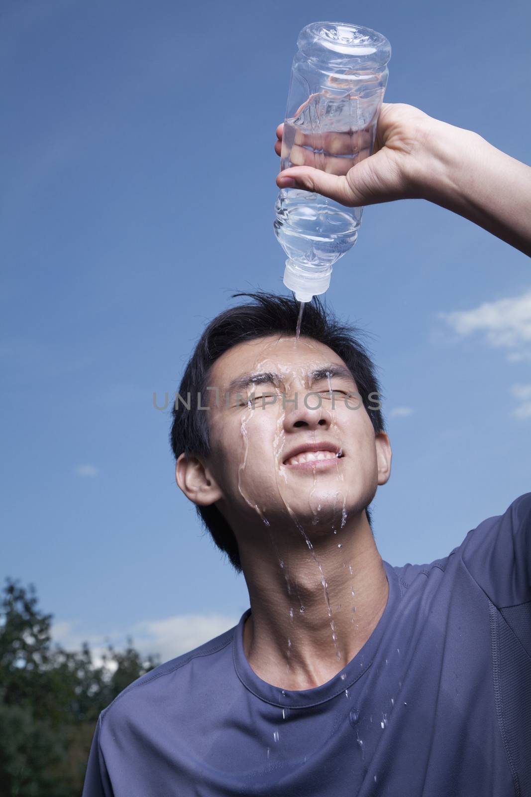 Young Man Pouring Bottled Water Over His Head