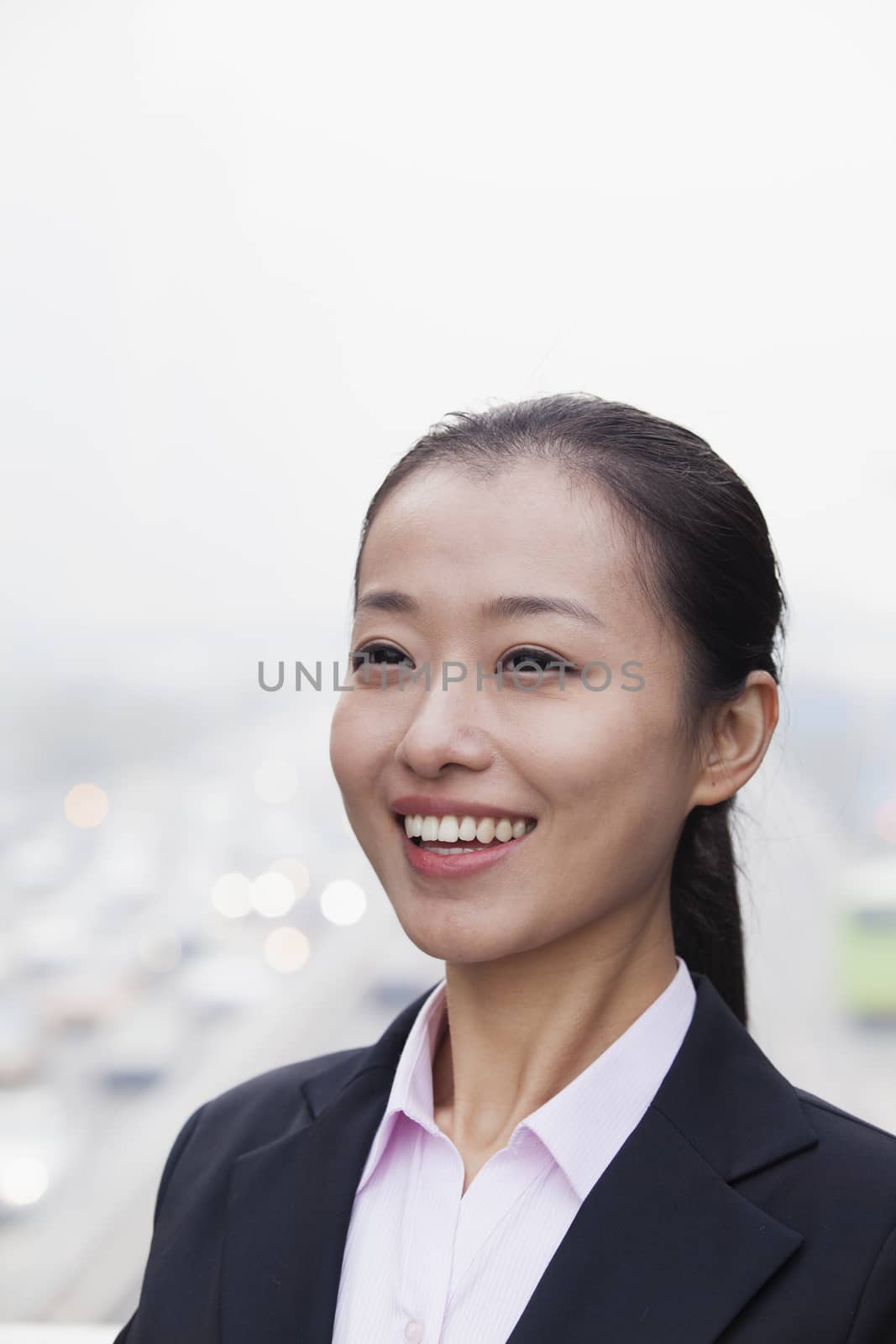 Portrait of Young Businesswoman Looking at Camera with Traffic Below by XiXinXing