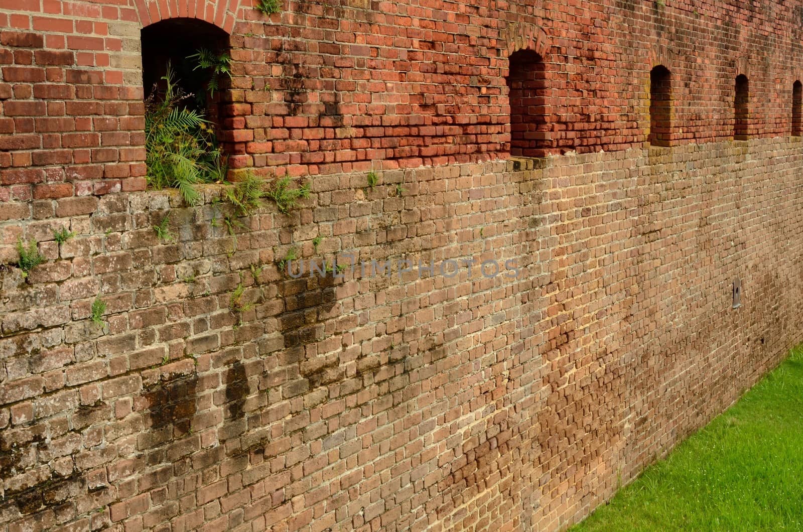 A brick wall with gun portholes in a Civil War era fort, Fort Clinch, which can be seen in Florida at Fort Clinch State Park